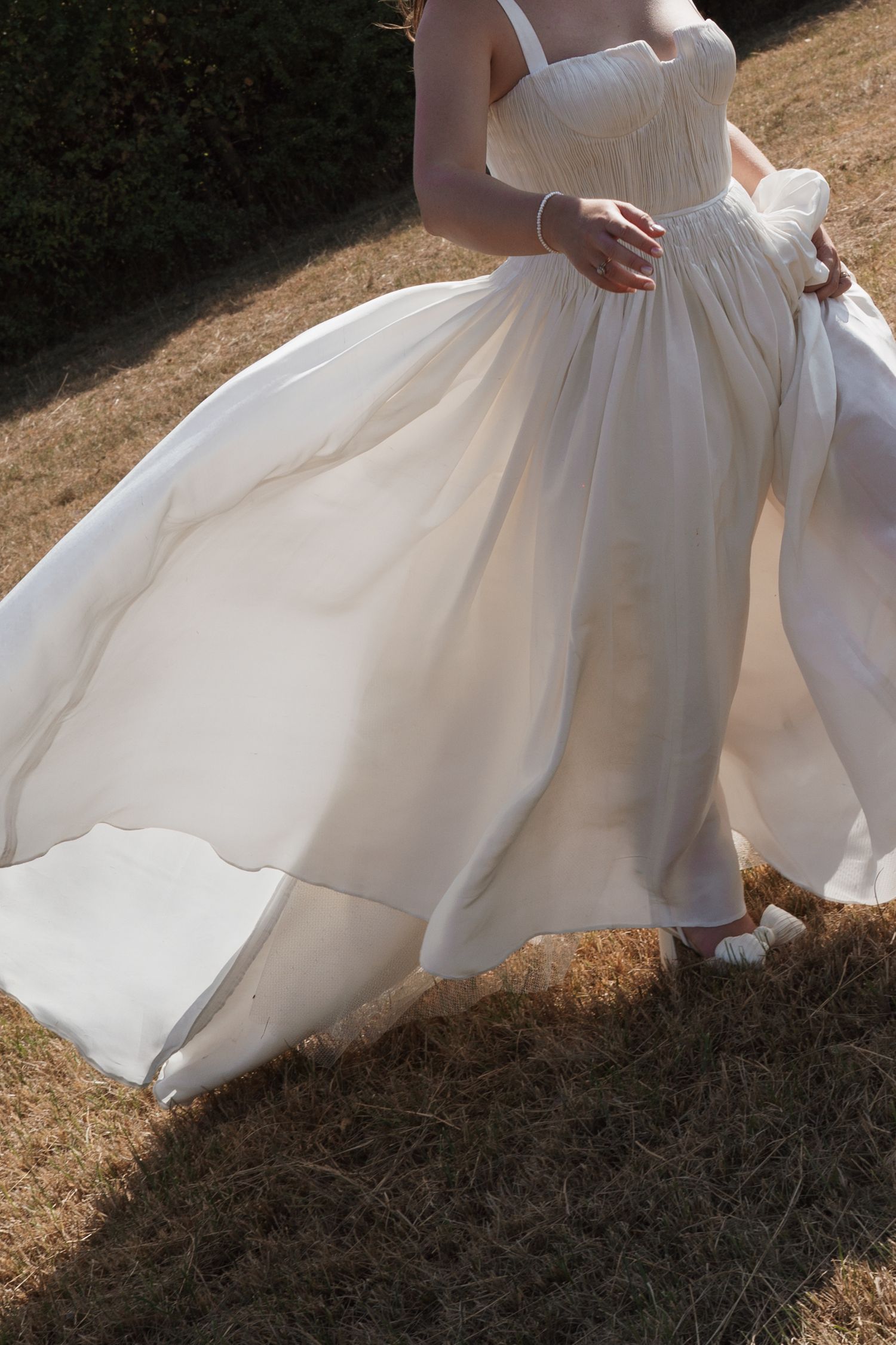 Close-up shots of flowing white wedding dress movement in sunlight.
