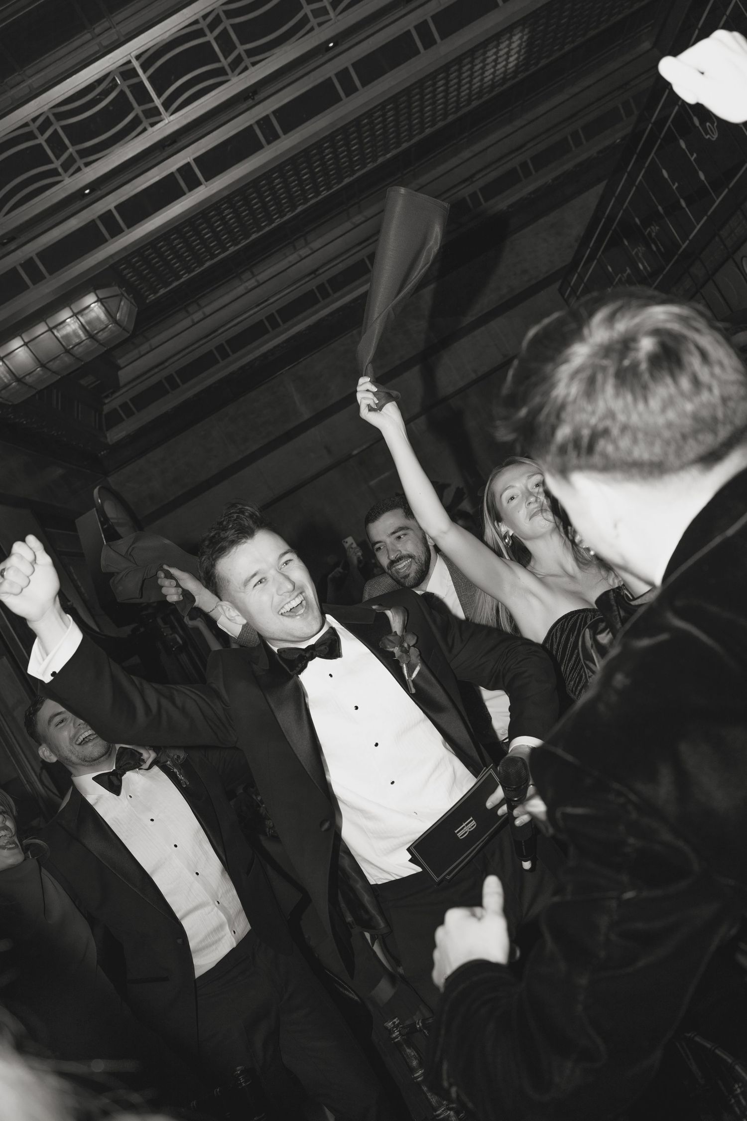 Black and white photo of formal event with guests dancing and celebrating.