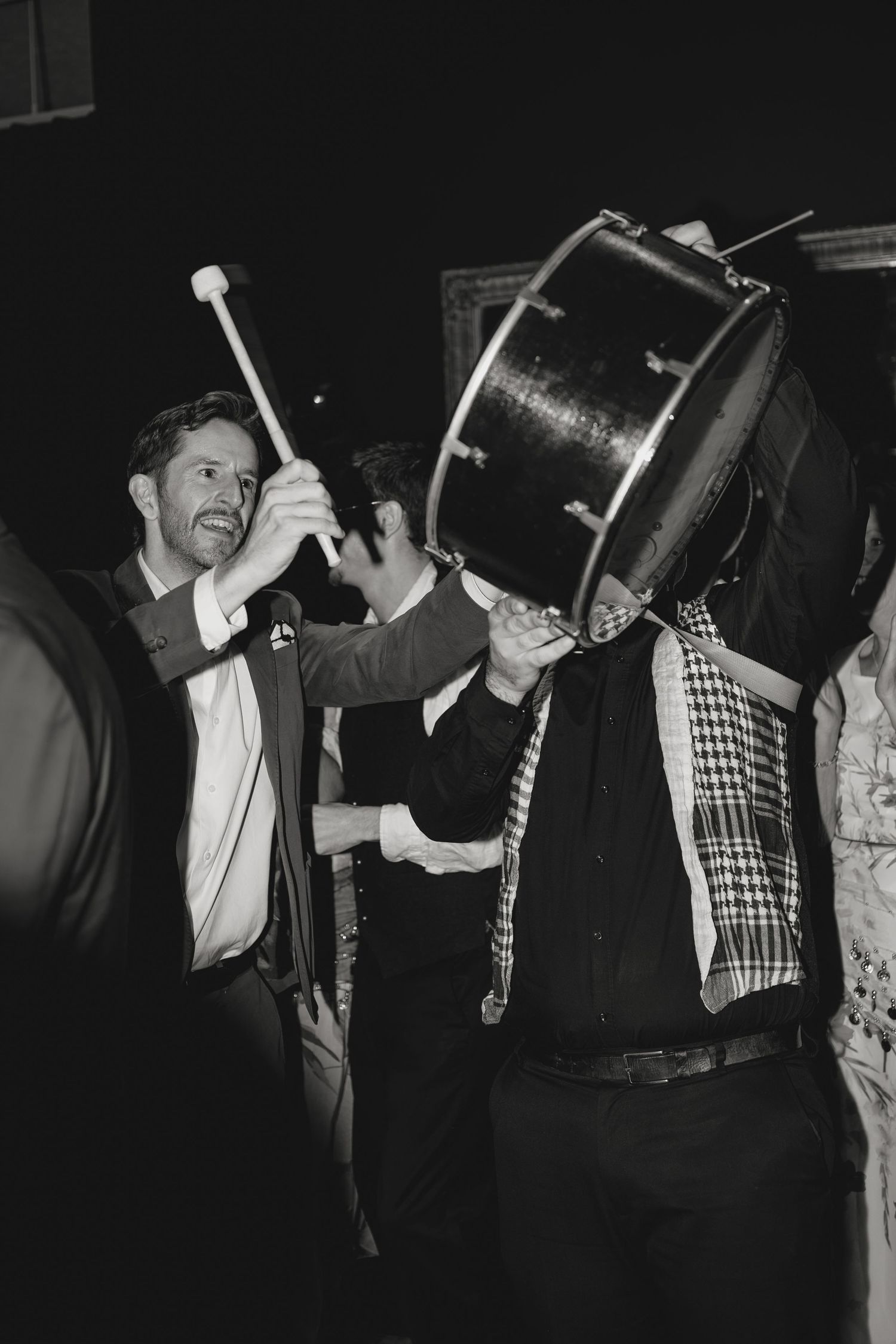 Celebratory moment with a large drum being held up during a festive gathering.
