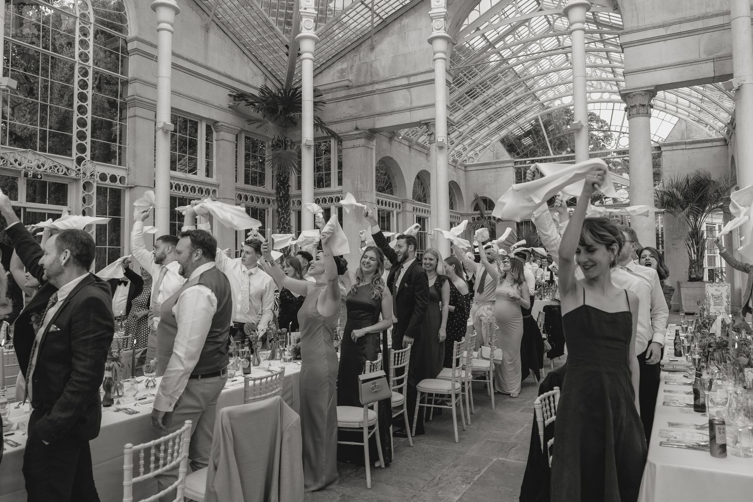 Elegant wedding reception in a grand conservatory with glass ceiling and ornate architecture.