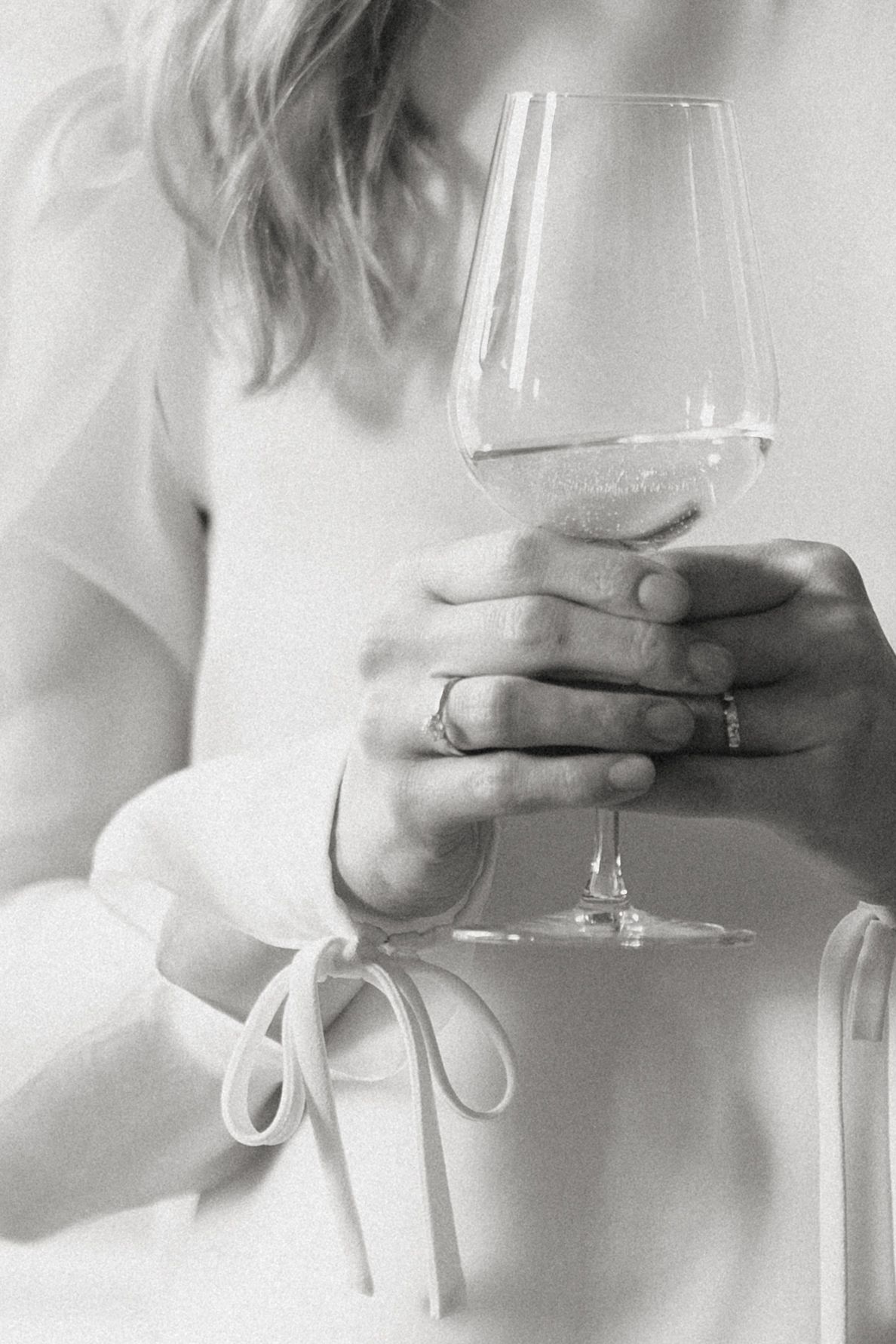 Hands holding wine glass against white background in minimalist style.