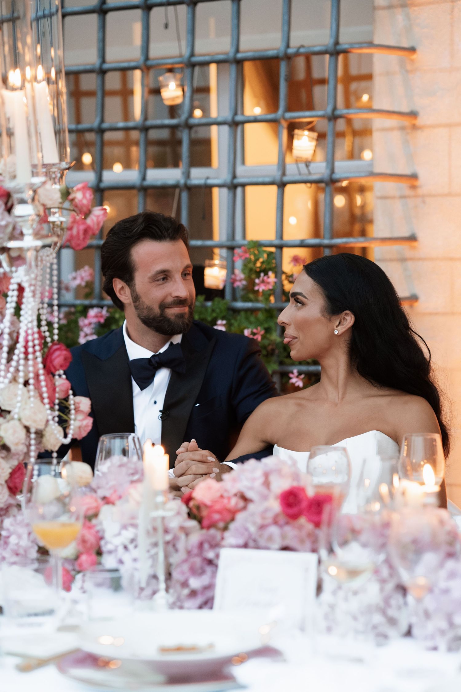 Elegant wedding reception table decorated with pink flowers and crystal details.