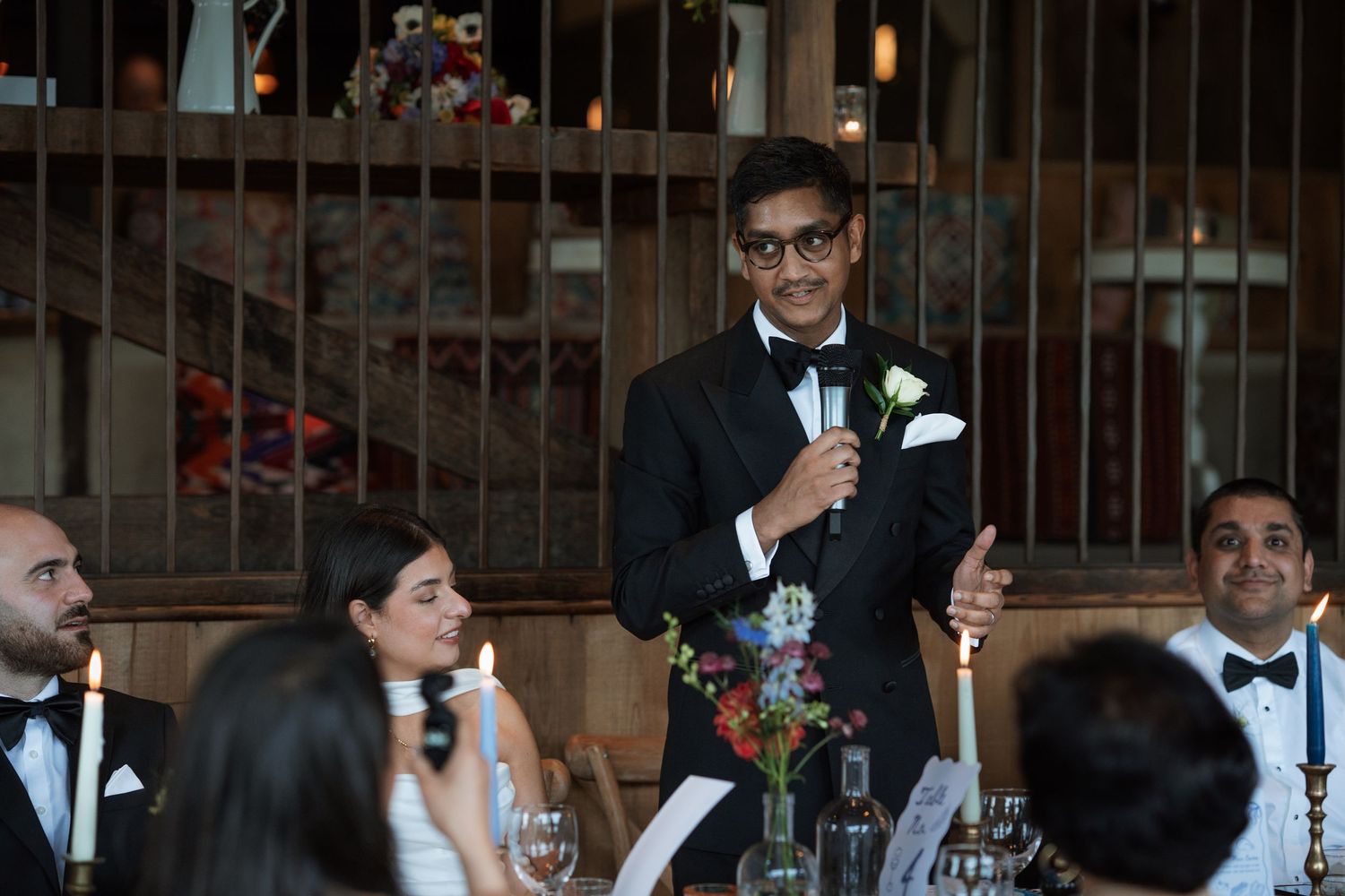 Wedding reception guests listening attentively to speeches in an elegant indoor venue.