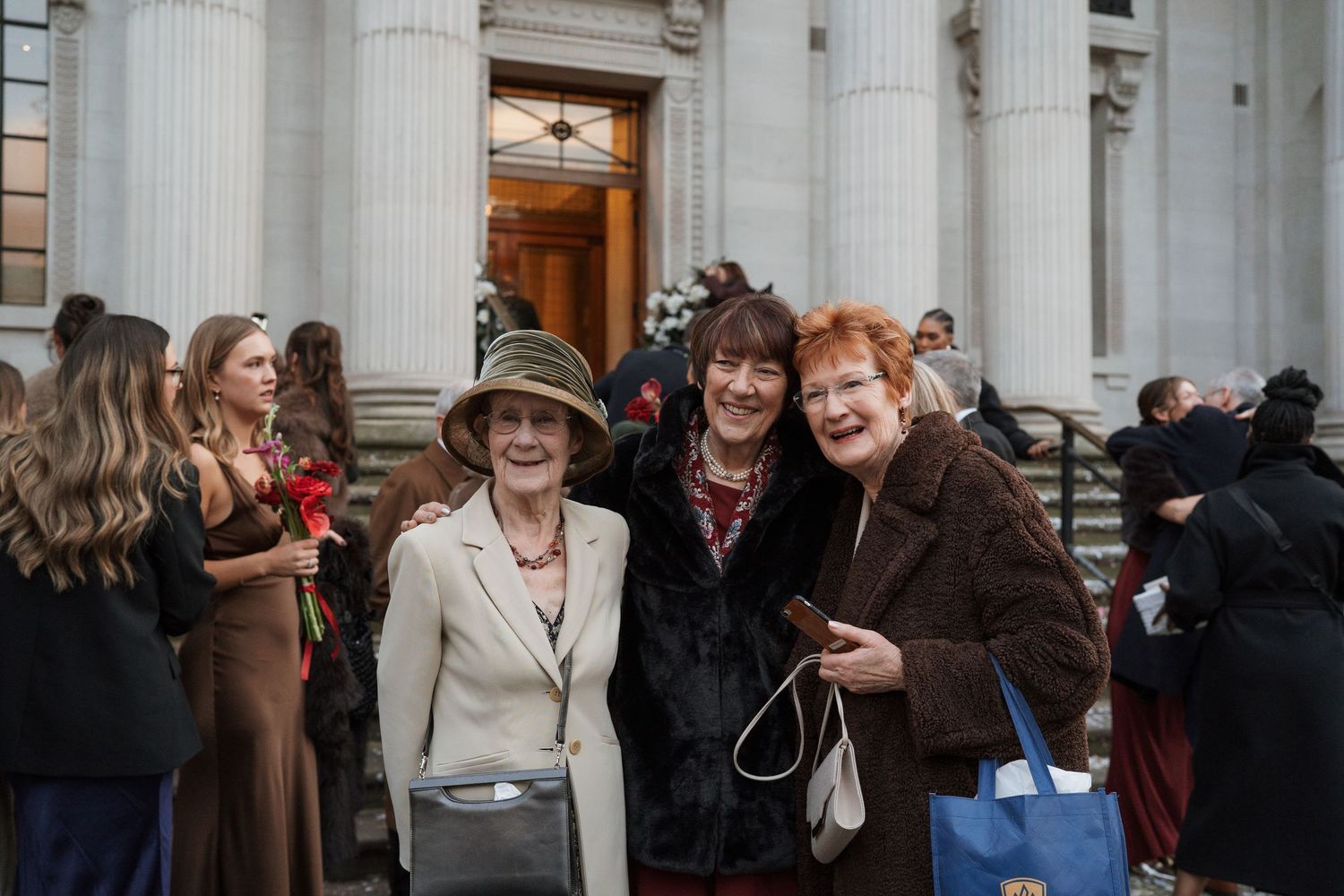 Guests mingle outside a classical building with white columns.
