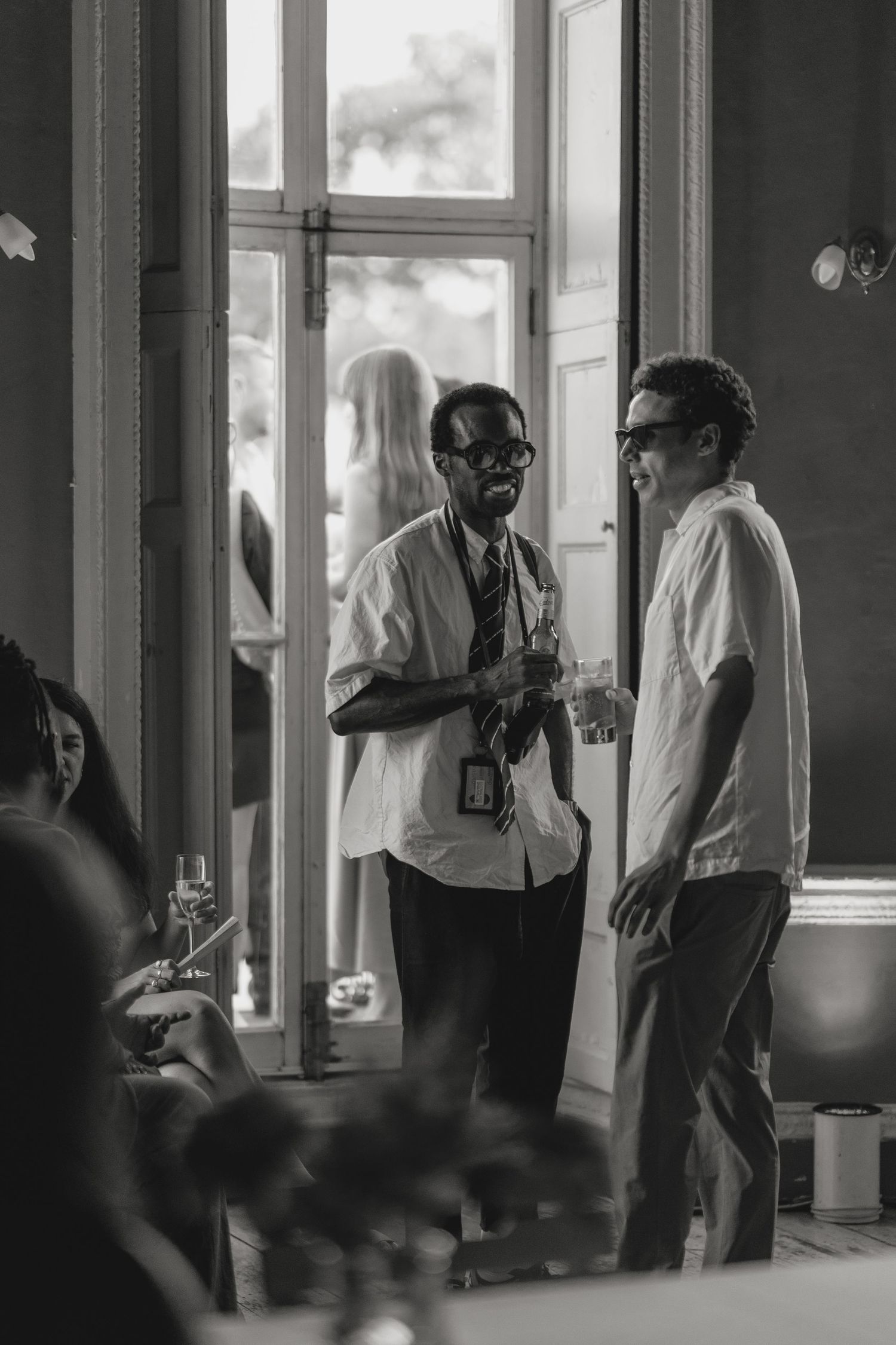 Photographers in formal attire gather near windows at a wedding event.