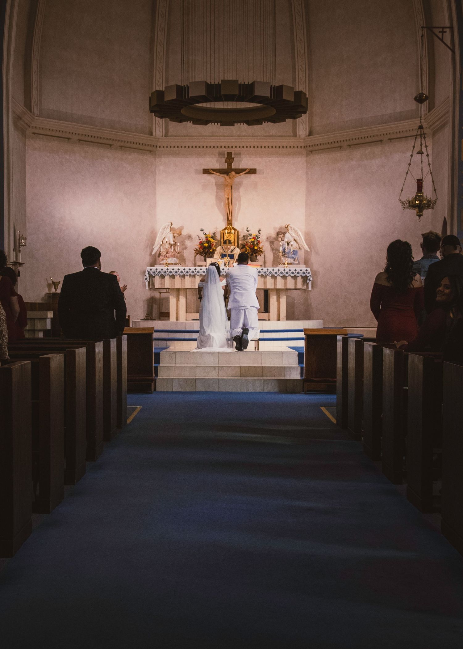 Wide view of a church sanctuary with wooden pews leading to an illuminated altar.