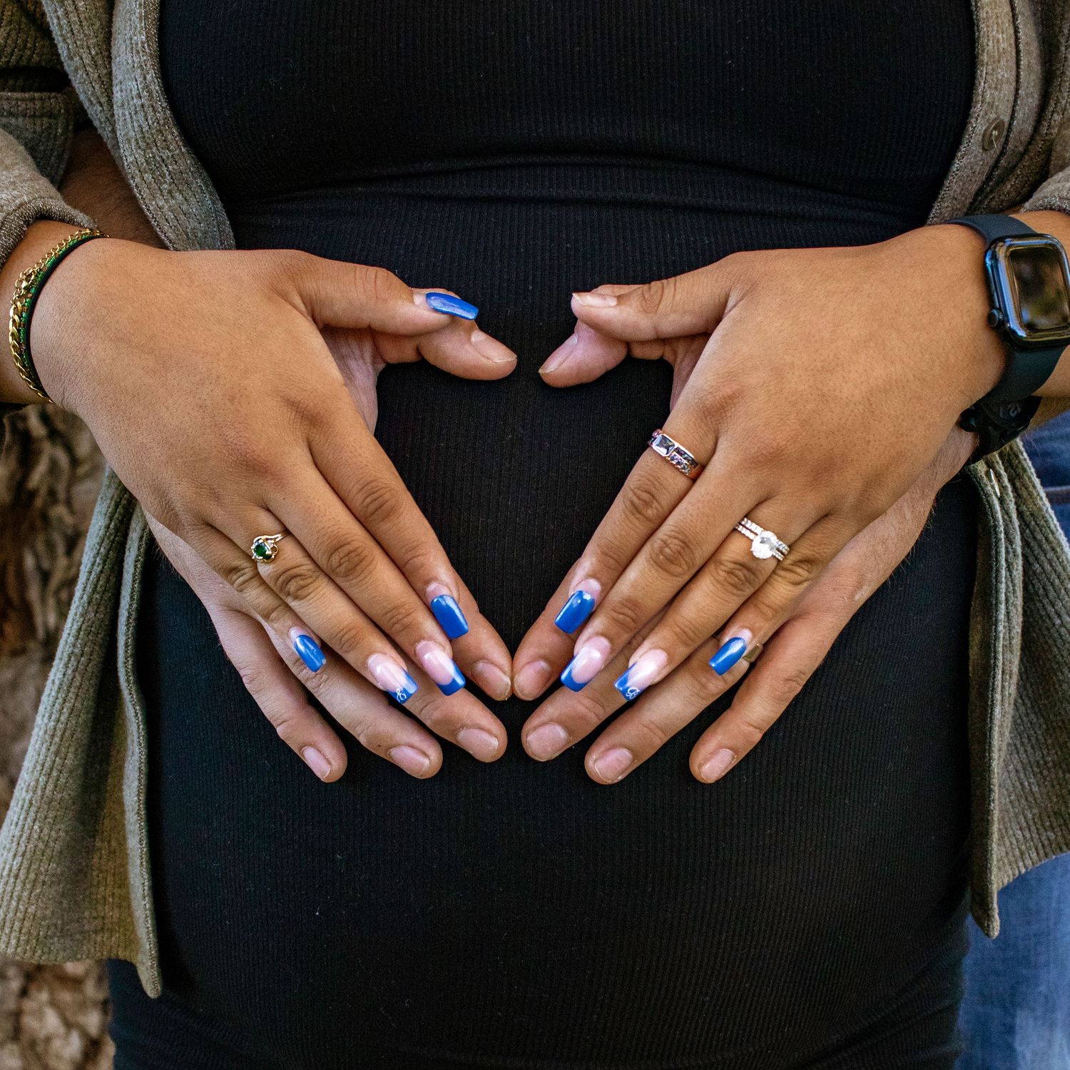 Close-up of hands showing off rings and blue nail polish.