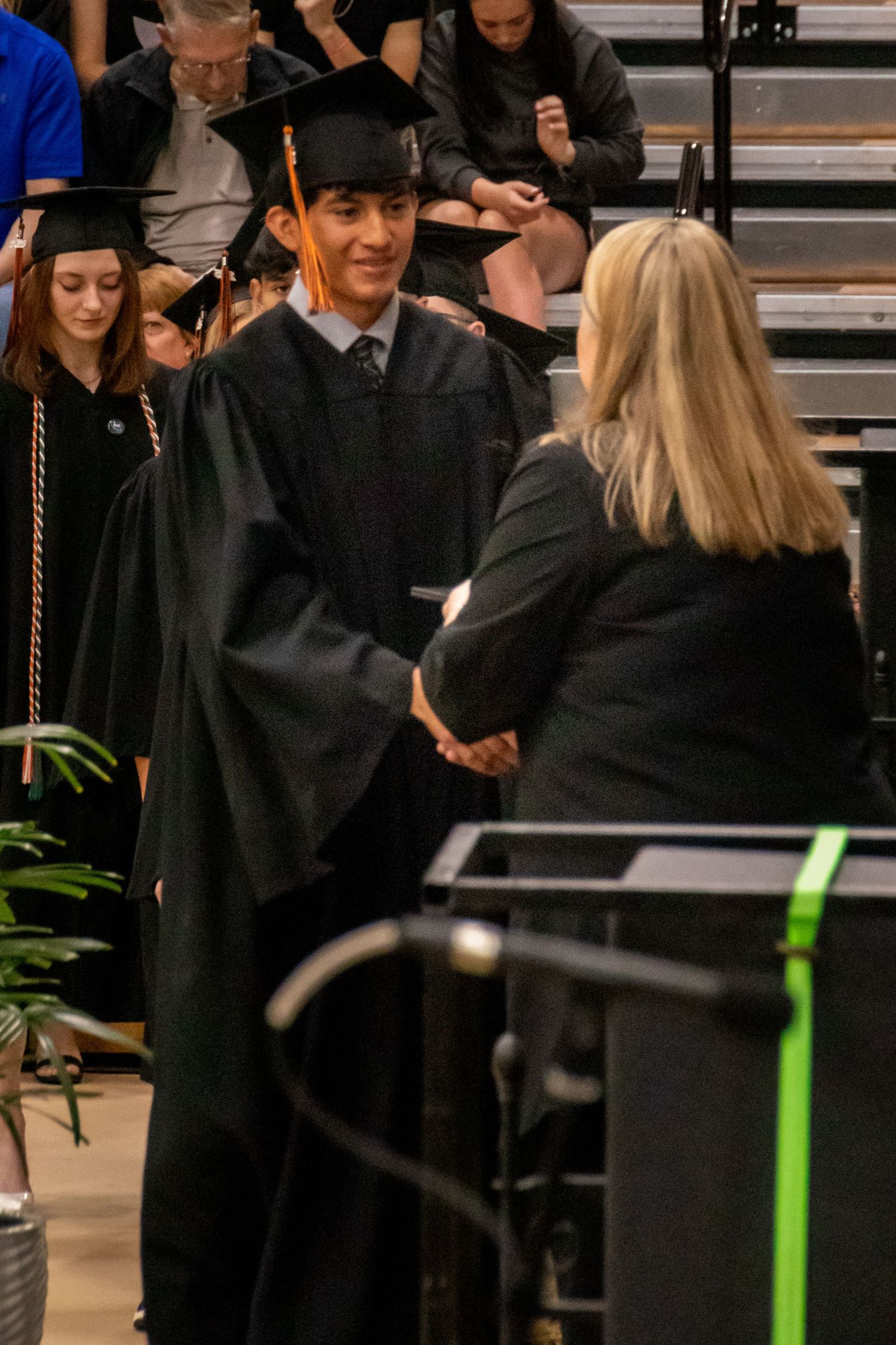 Graduate in black cap and gown receives diploma during ceremony.