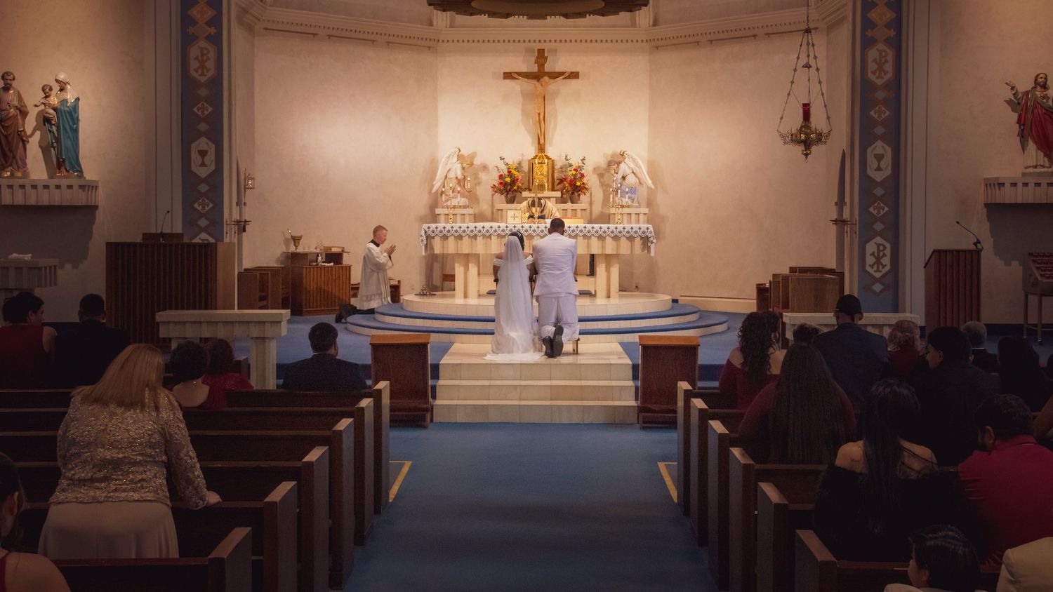 Interior of a Catholic church with pews and altar visible under warm lighting.