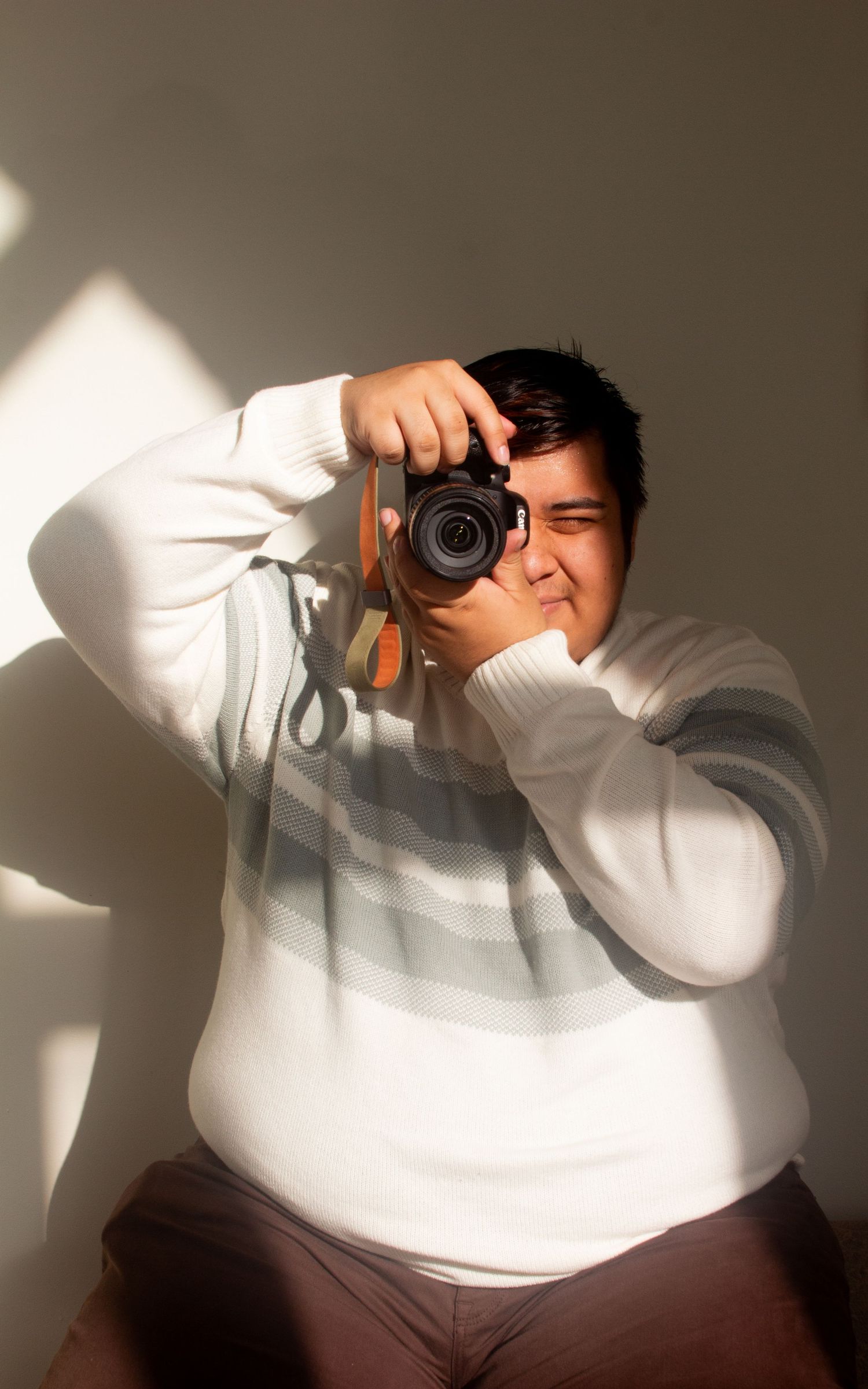 Artistic portrait series showing someone taking photos in dramatic window lighting.