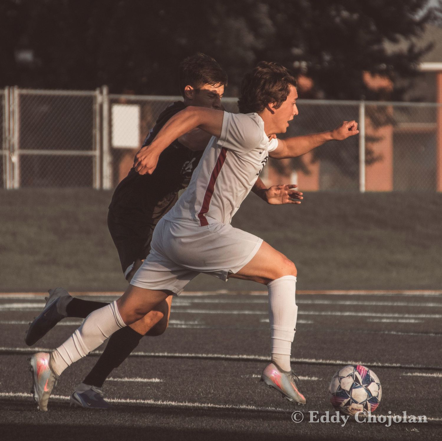 Soccer player in white uniform kicking ball during intense match on field.