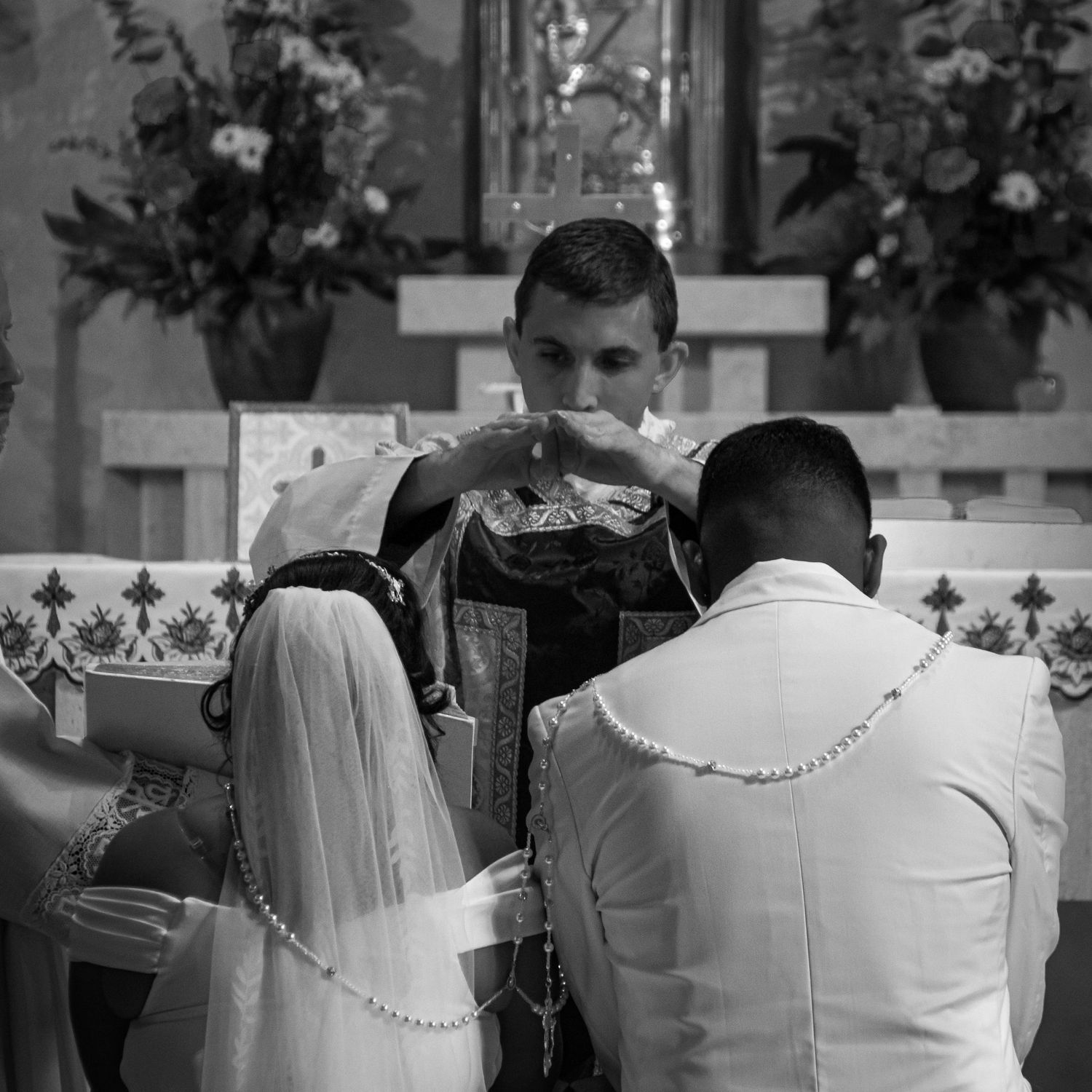 Wedding guests in formal white attire seated in church pews.