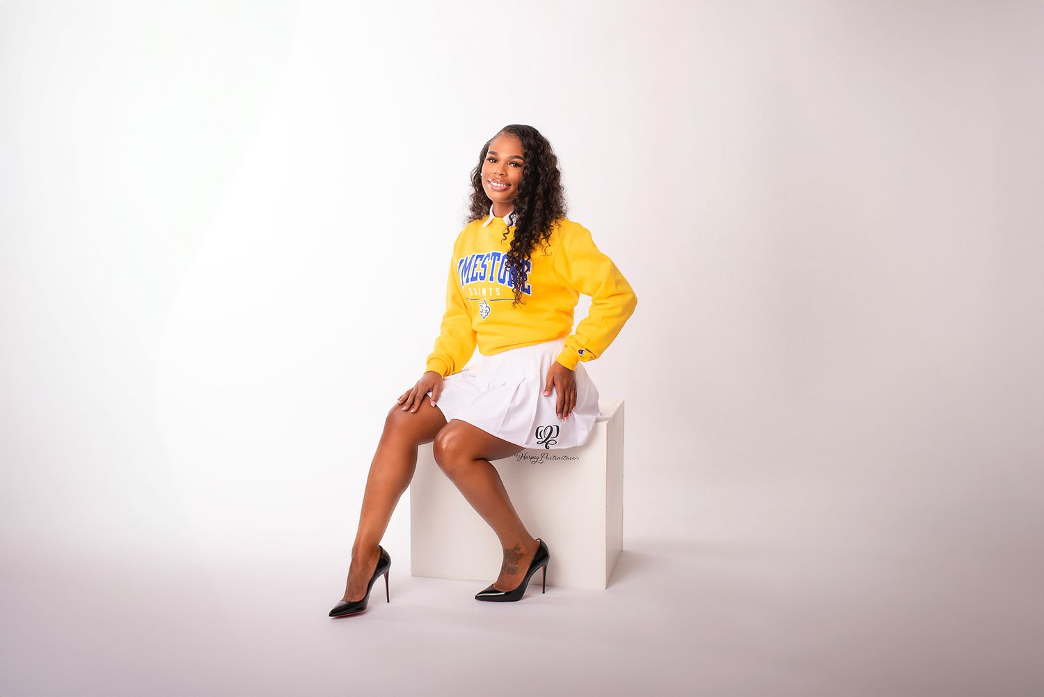 Senior photographer Lexington, SC; young female in school colors poses on white box in studio senior photoshoot