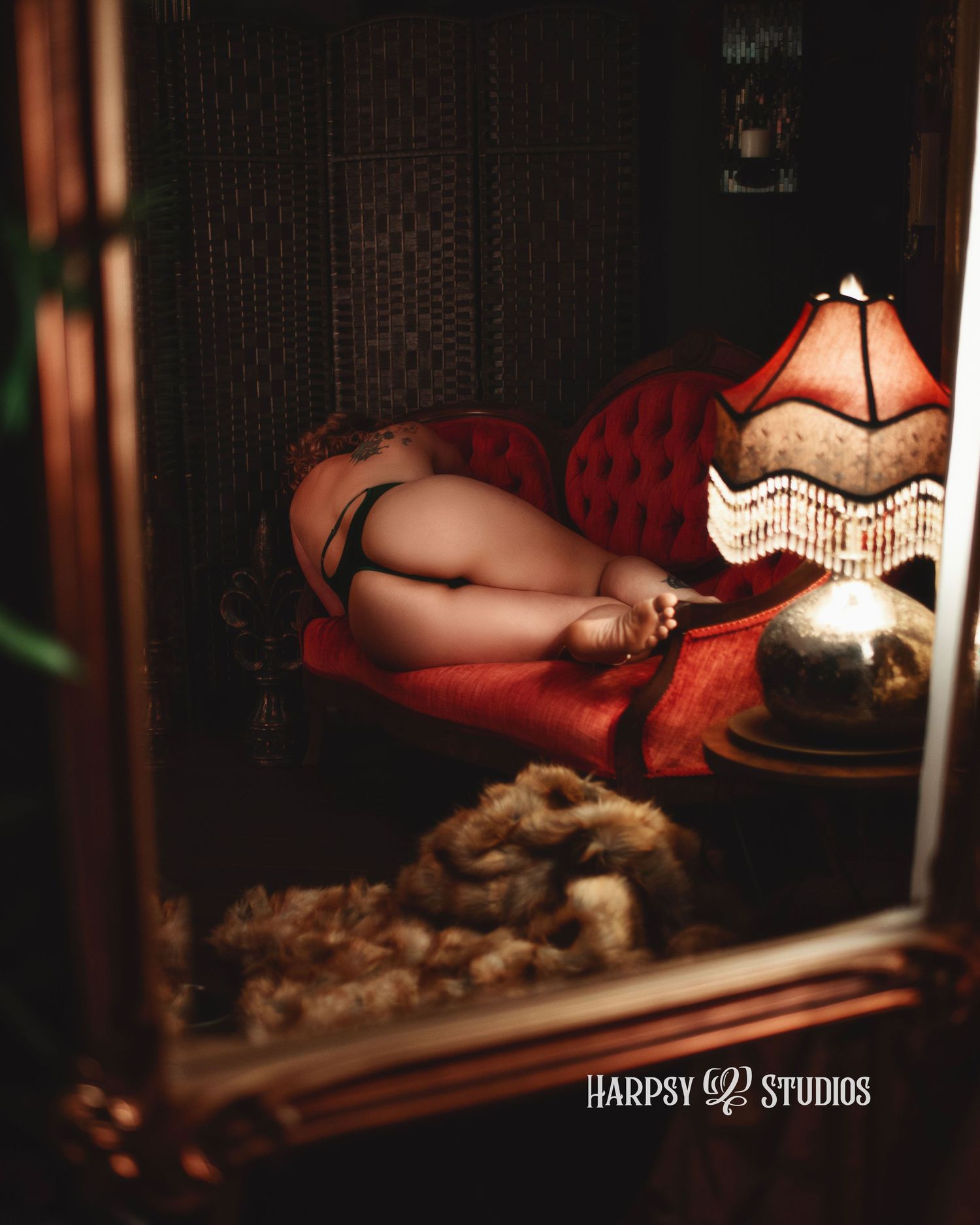 Boudoir photography in Lexington, SC, professional boudoir studio; reflection in mirror of sexy female lying on couch with bare bum visible