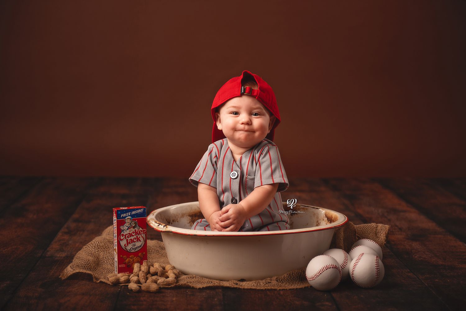 Baby boy sitting in prop with baseball uniform & hat with baseballs; Lexington, SC children's photographer; indoor pictu
