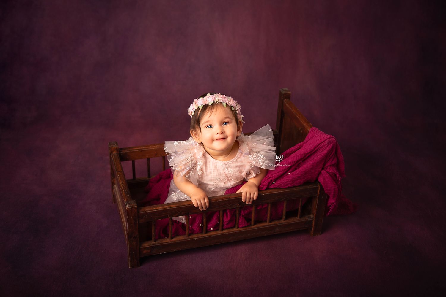Baby girl smiling at camera in pink tulle dress & flower headband on purple indoor studio backdrop; Lexington, SC photog