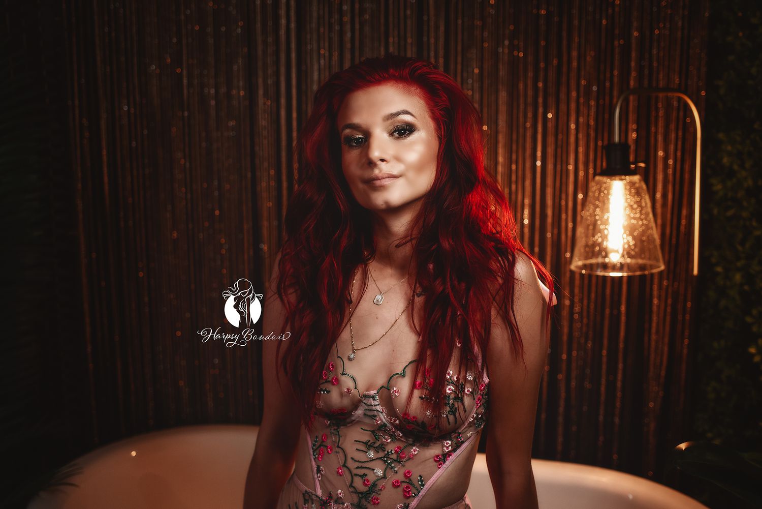 Luxury boudoir photography in Lexington, SC, professional boudoir studio; redhead female wearing lingerie smirks at camera with glowing lamp