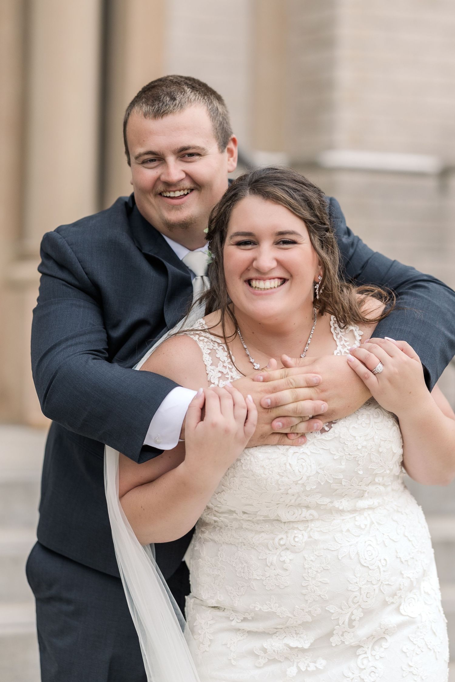 A couple shares a joyful embrace during their wedding portraits.