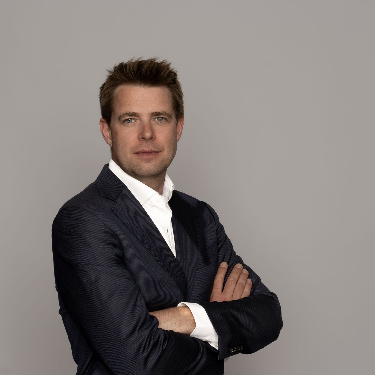 Professional headshot series showing a person in dark suit and white shirt against neutral gray background. Zakelijke fotografie Almere