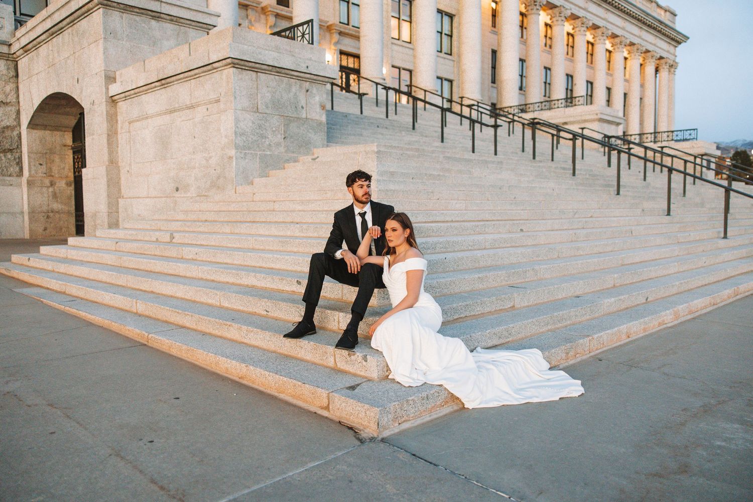 Bride and groom sitting on the steps of the Utah State Capitol during a bridal photo session