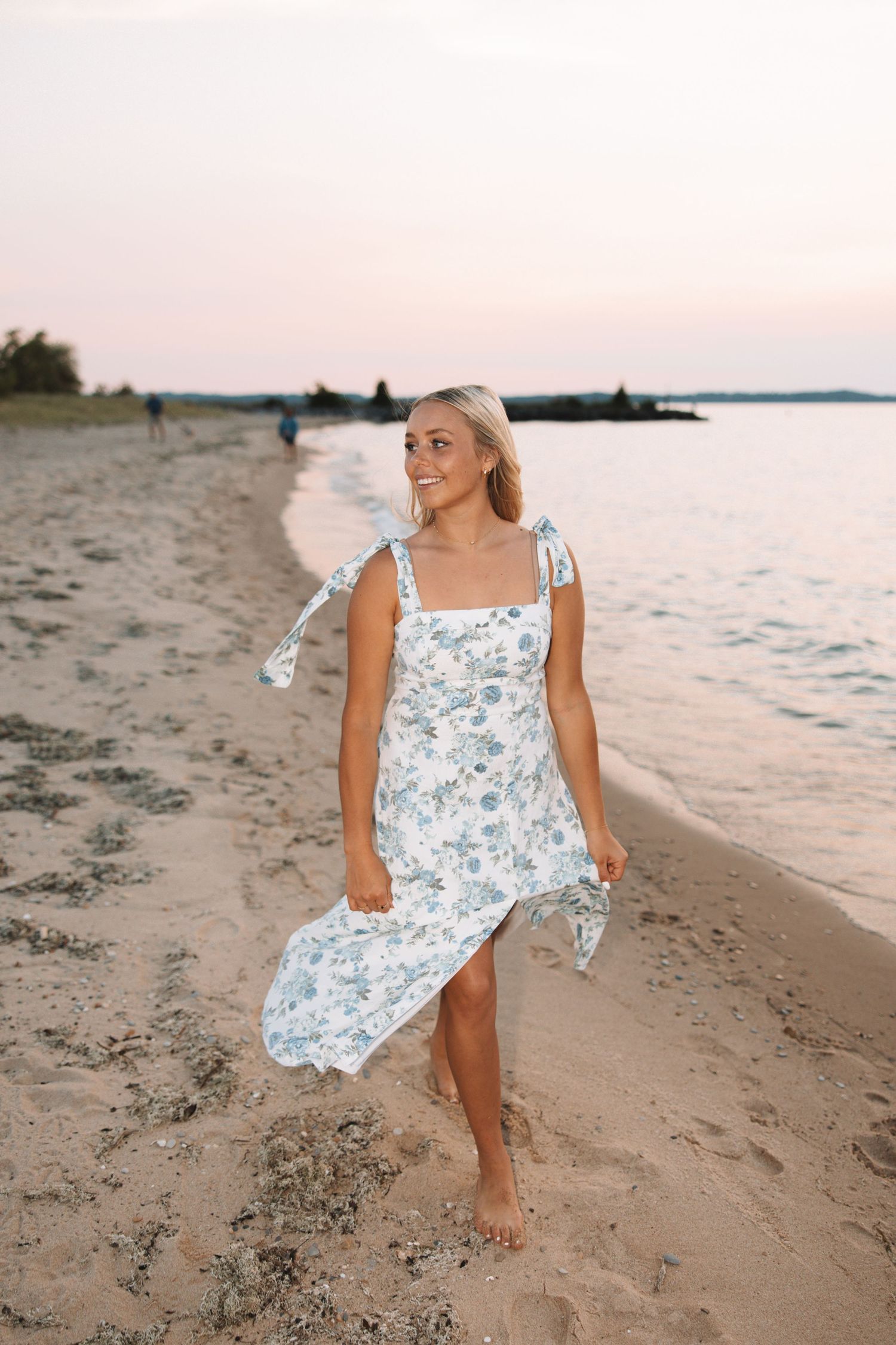 Senior portrait of a young woman walking along the beach during a sunset photo session