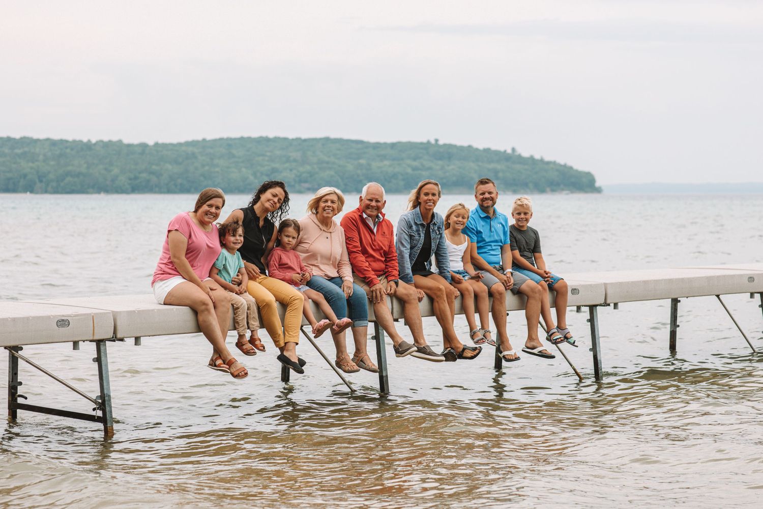 Family sitting together on a dock by the water during a relaxed summer photo session