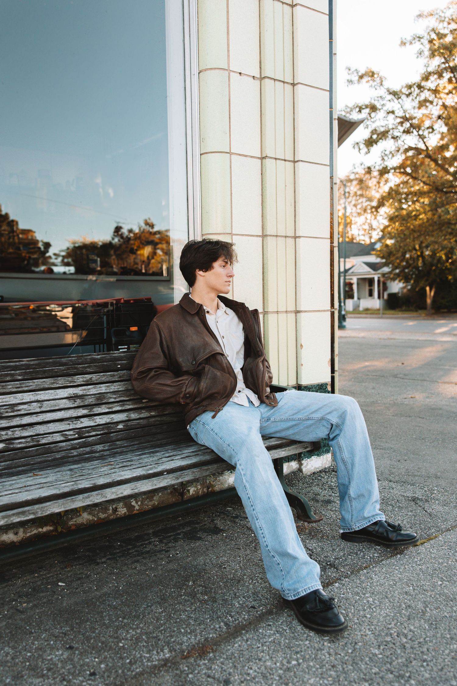 Senior portrait of a young man sitting on a bench in an urban setting during golden hour