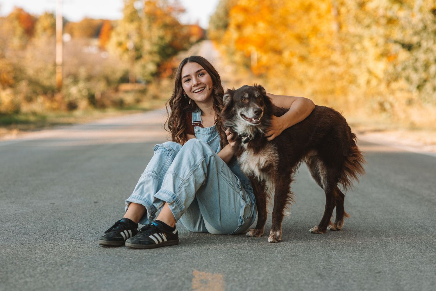 Girl senior with her dog sits for photos in Traverse City, Michigan for a photoshoot for high school senior photos.
