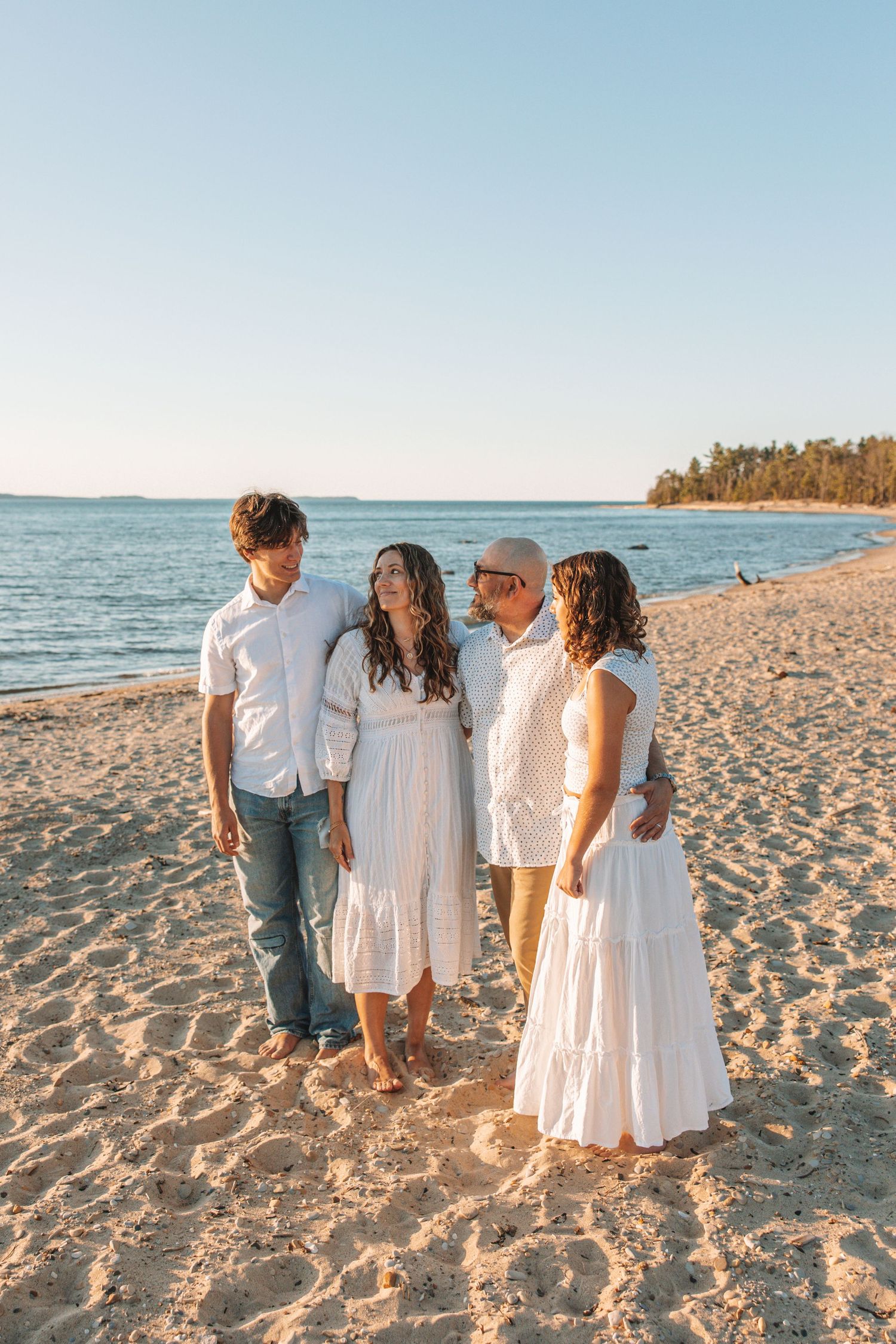 Family walking along a sandy beach together during a sunset family photo session In Traverse City, Michigan
