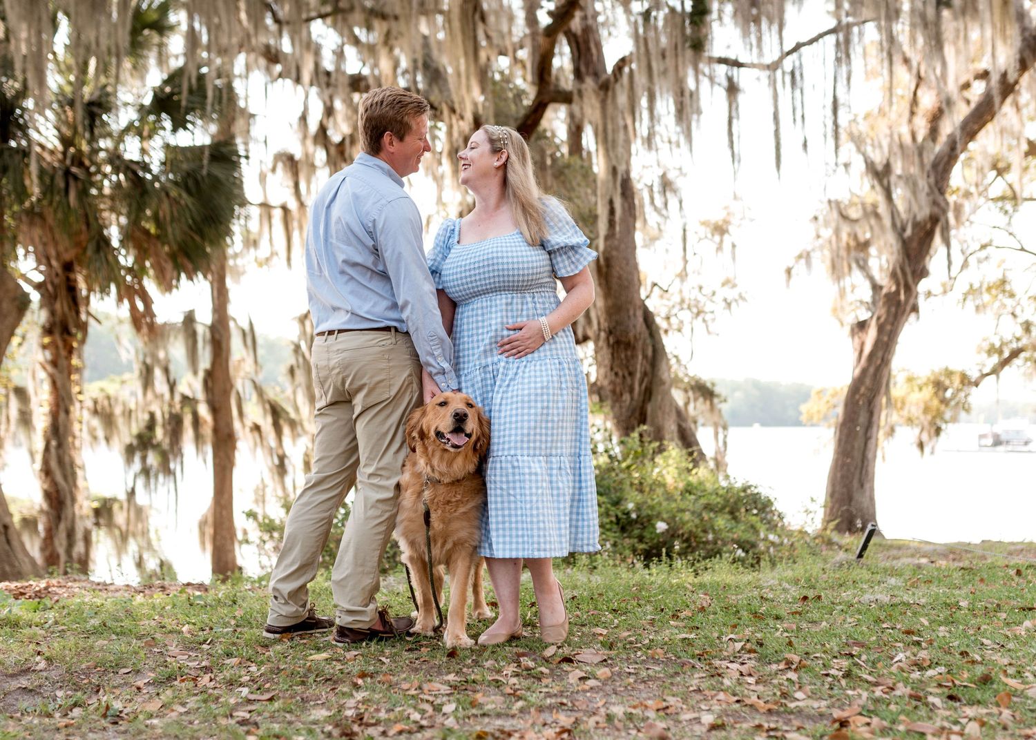 Couple embracing under Spanish moss trees during outdoor photo session.