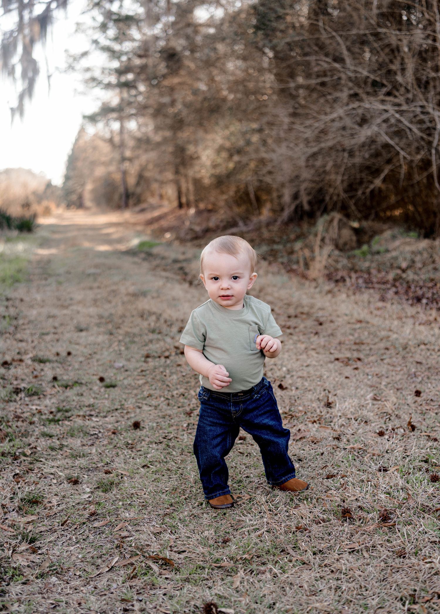 Baby taking first steps outdoors in natural wooded setting.