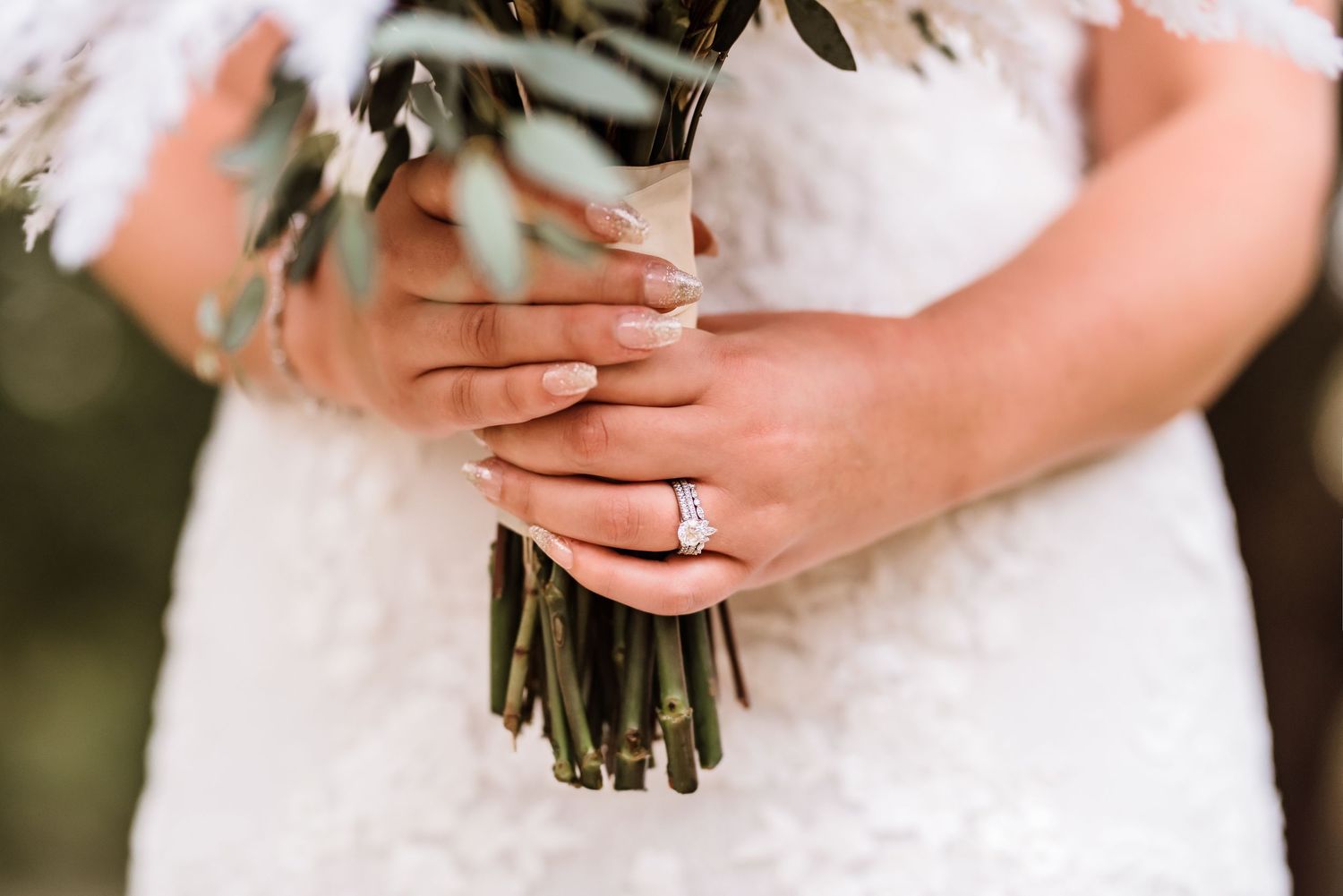 Close-up of bridal bouquet being held with wedding ring visible.