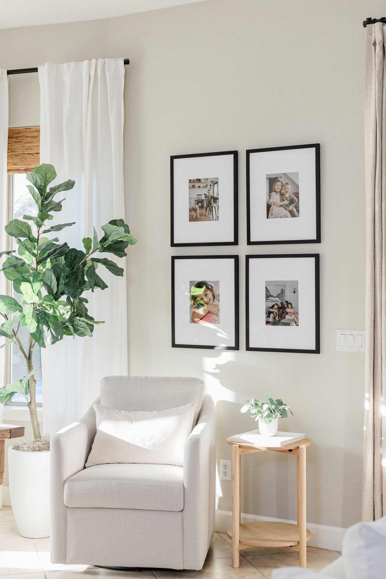 Modern minimalist living room with white armchairs, framed art, and fiddle leaf fig plant.
