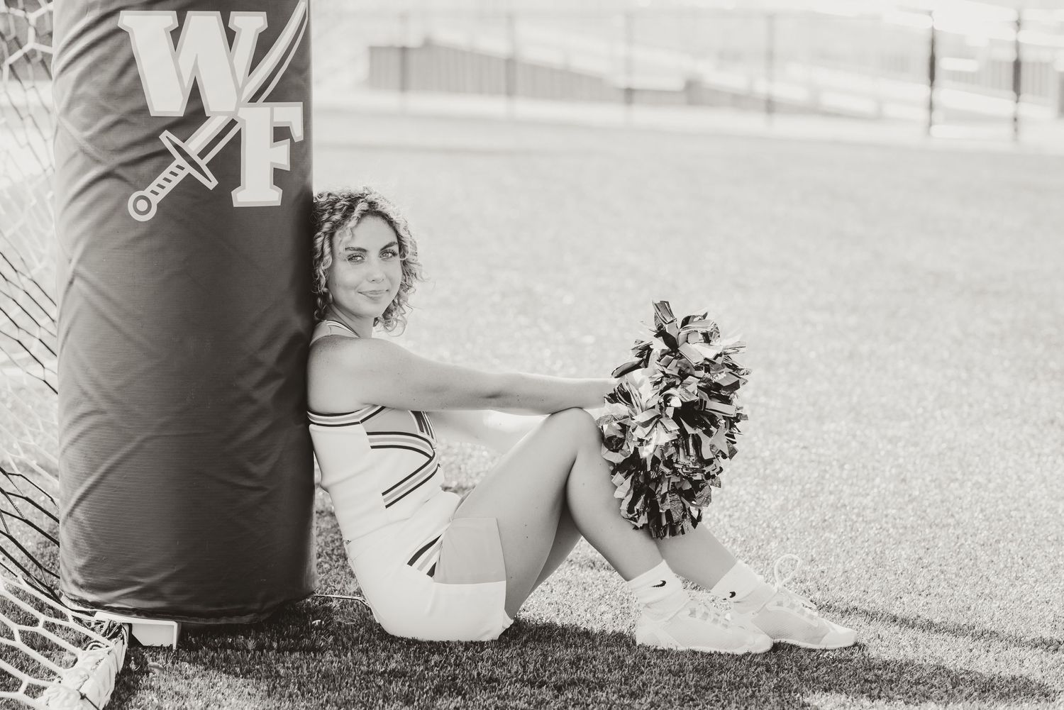 Black and white photo of cheerleading practice on sunny field.
