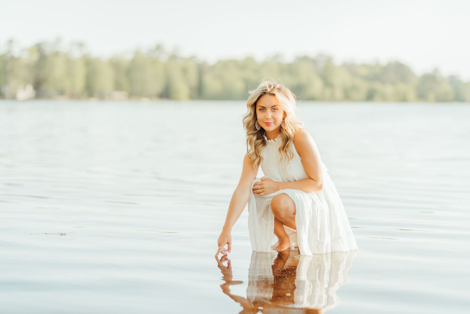 Someone in a white dress dancing joyfully near a serene lake.