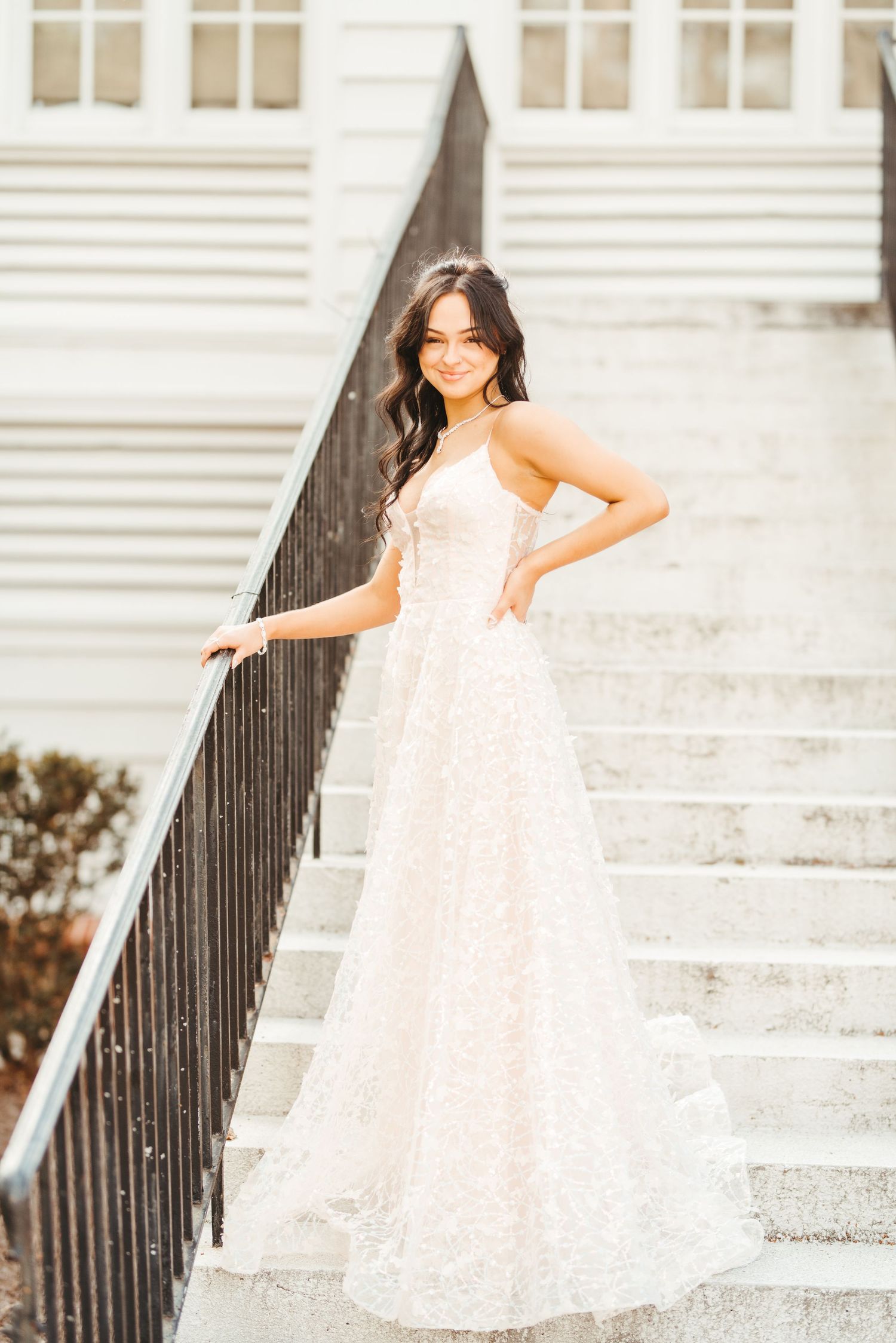 A stunning white wedding dress captured on historic steps with iron railing and white architecture.