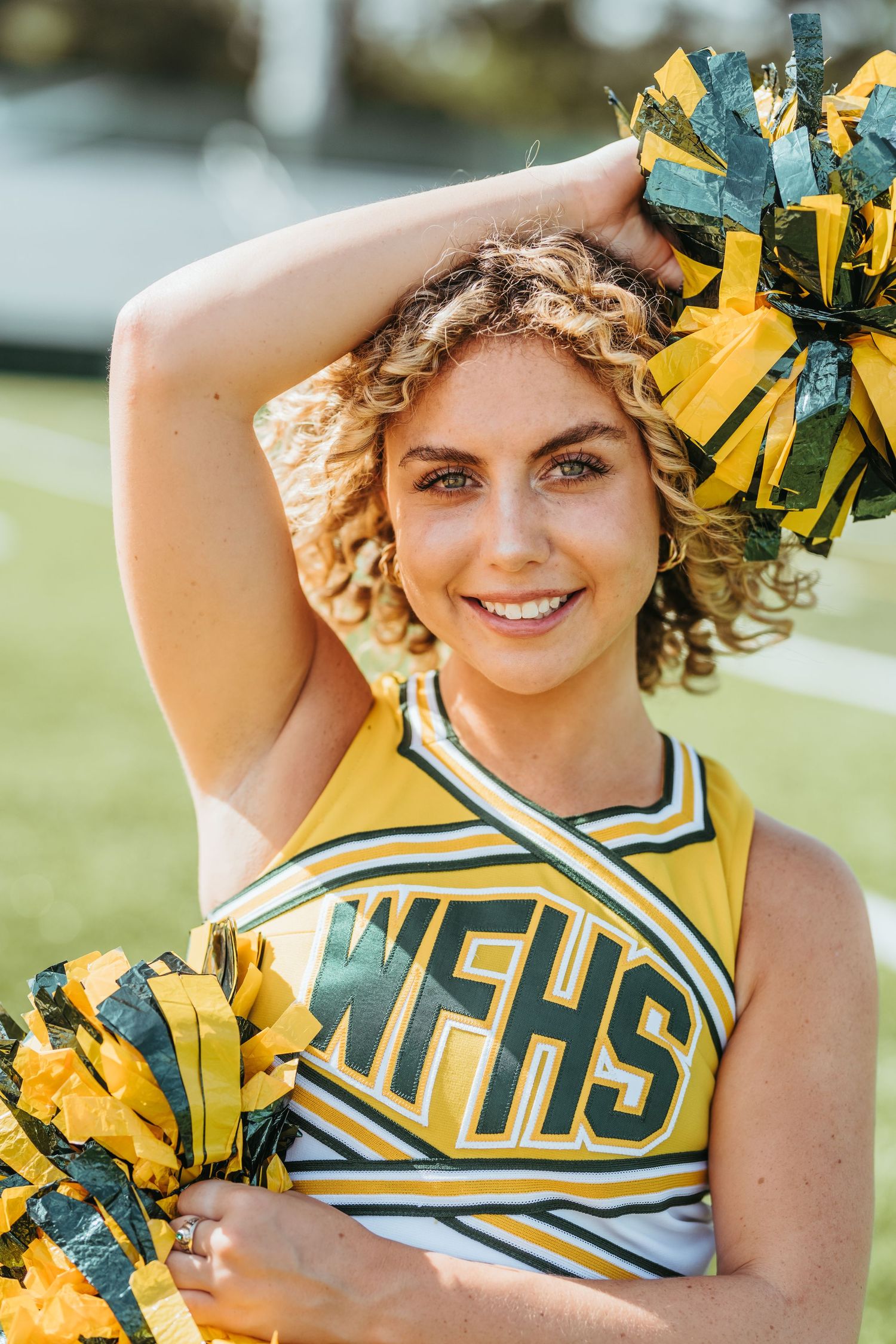 Cheerleader wearing yellow and navy uniform with pom poms in multiple poses.