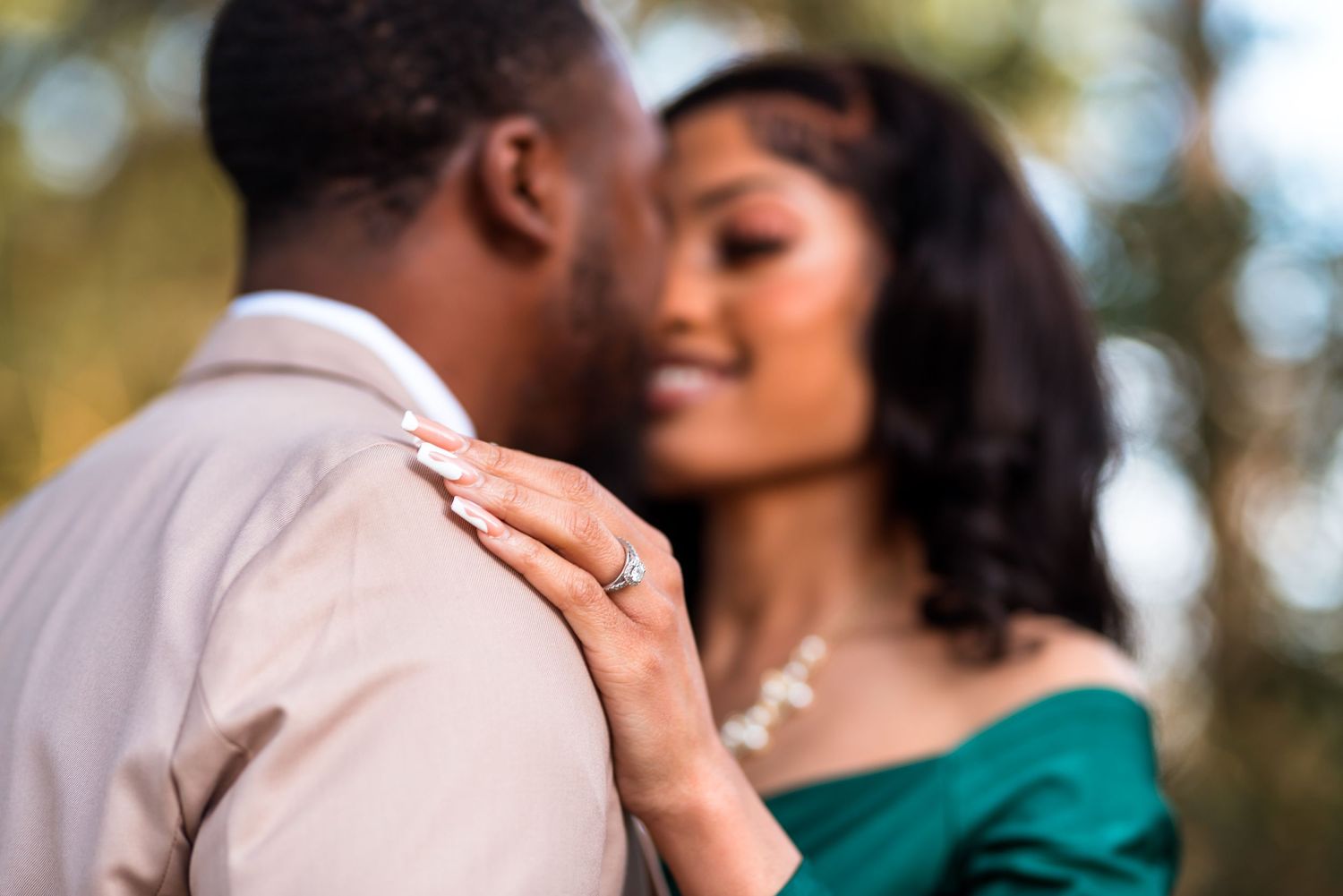 Romantic couple in green and white outfits embrace outdoors during sunset photo session.