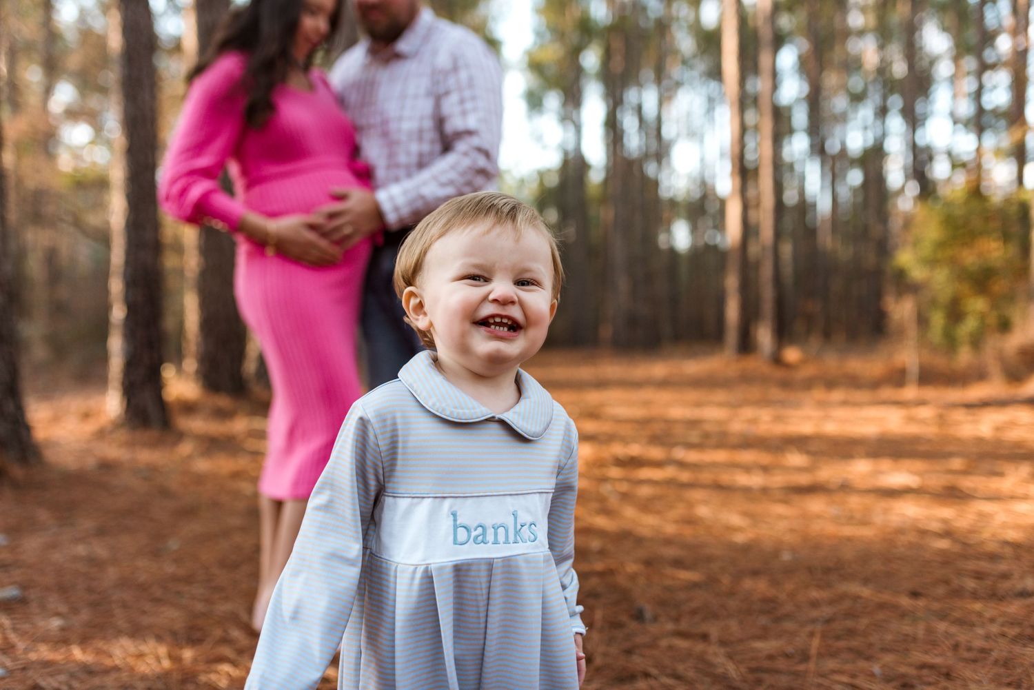 Family walking together on autumn path through pine forest.