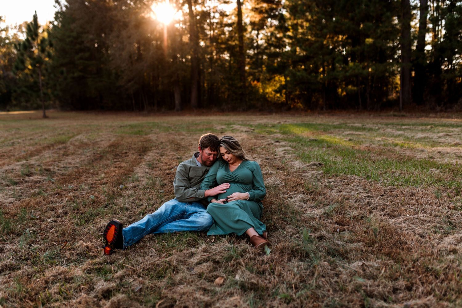 Couple relaxing together on grassy field during golden hour photoshoot.