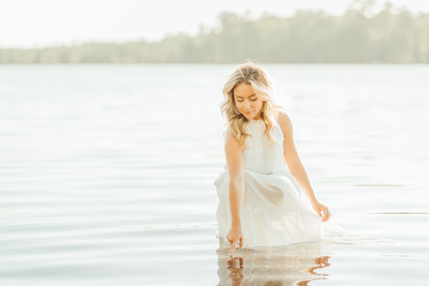 Figure in white dress twirling gracefully by the water's edge.
