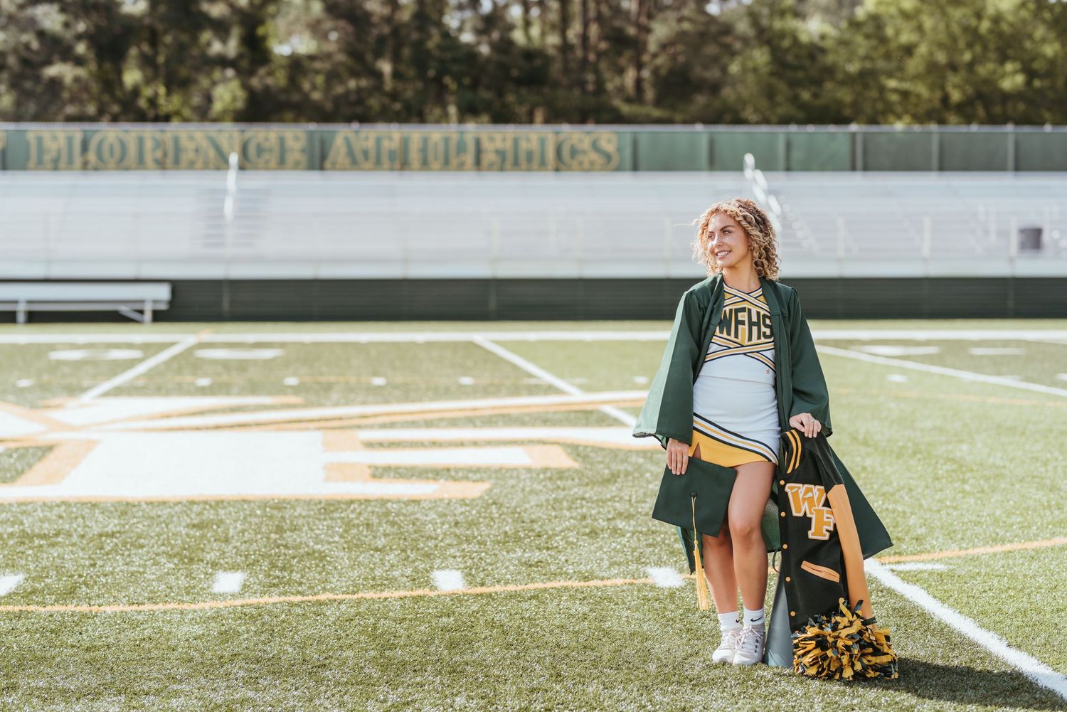 Football field with cheerleader and training equipment visible in afternoon sunlight.