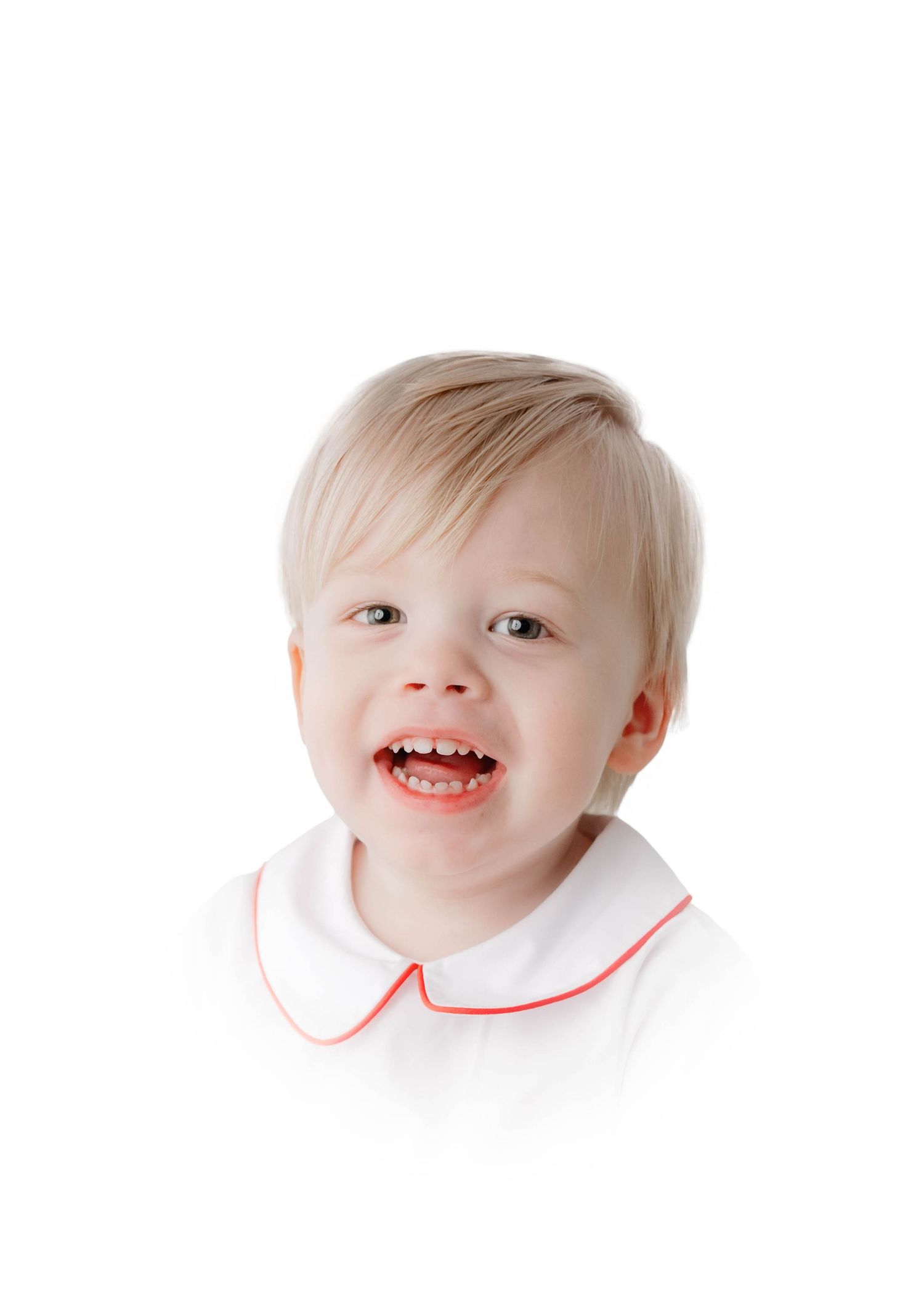 Smiling toddler with blonde hair wearing a white shirt with red trim on a white background.