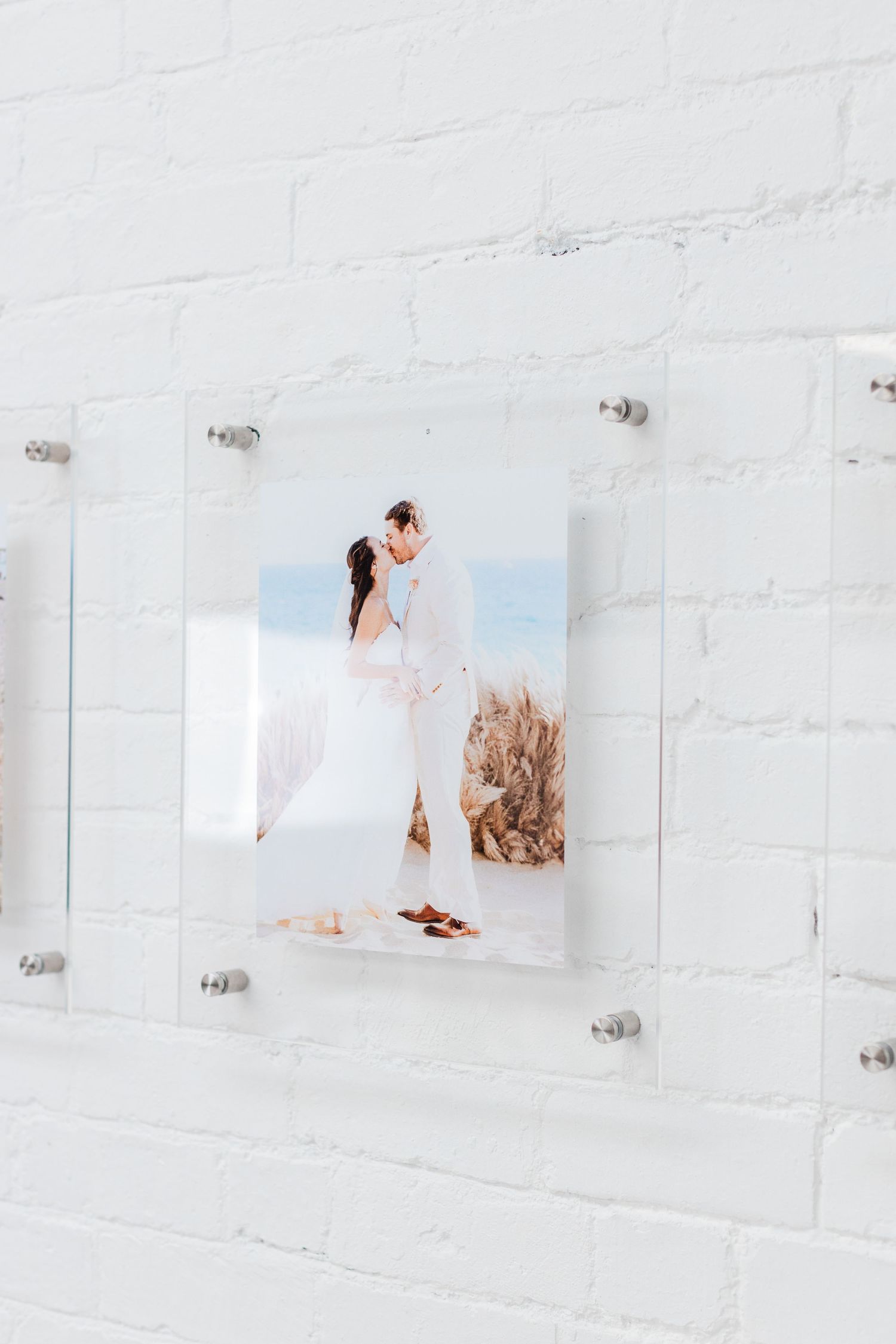 Row of white-framed photos mounted on textured white brick wall.
