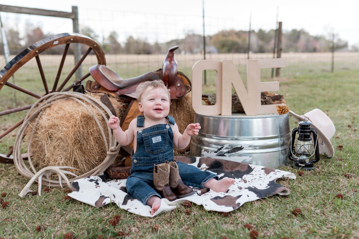 Rustic outdoor photo setup with vintage wagon wheel and denim overalls theme.