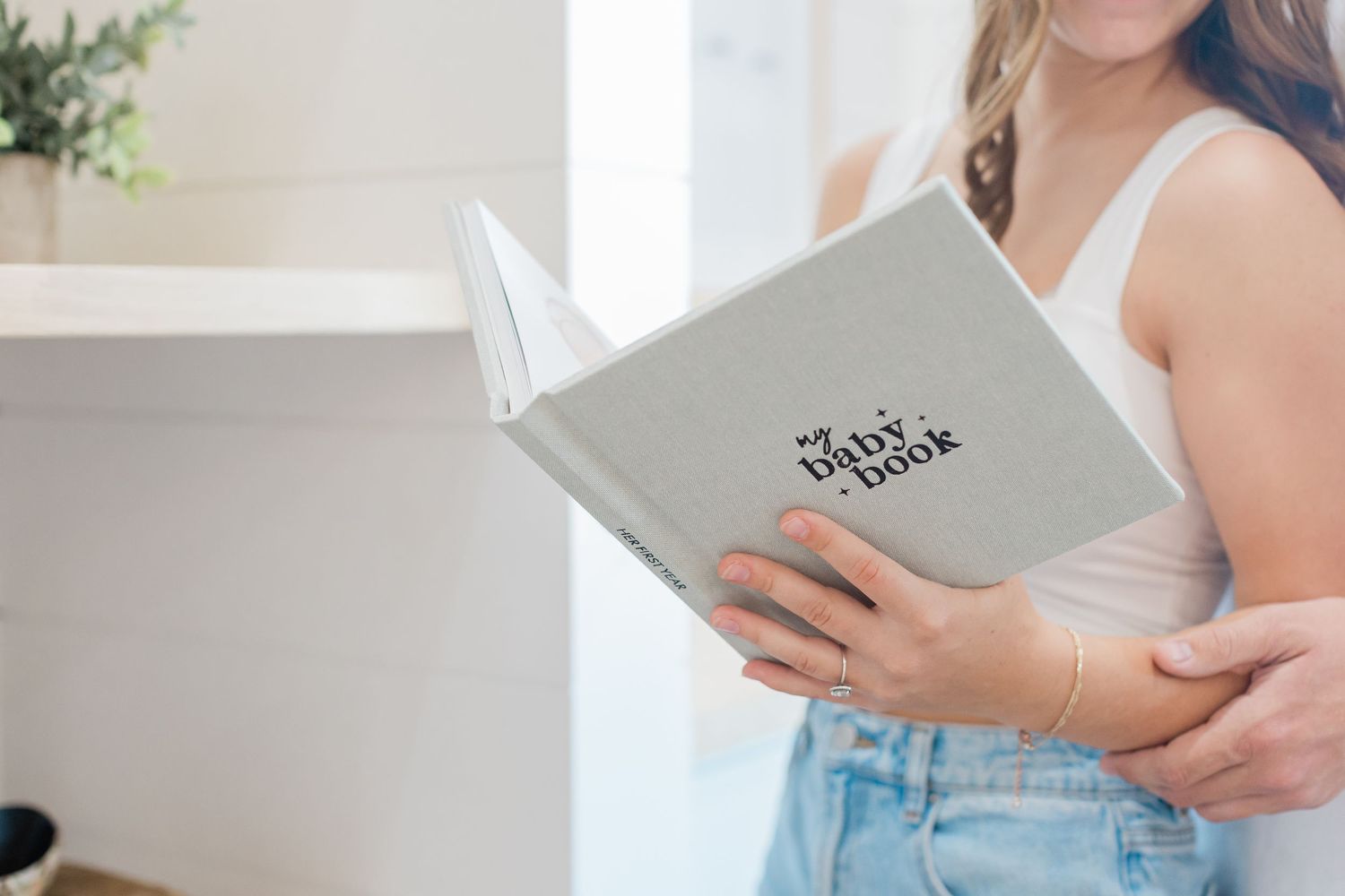 Person holding gray photo album or book against light background.