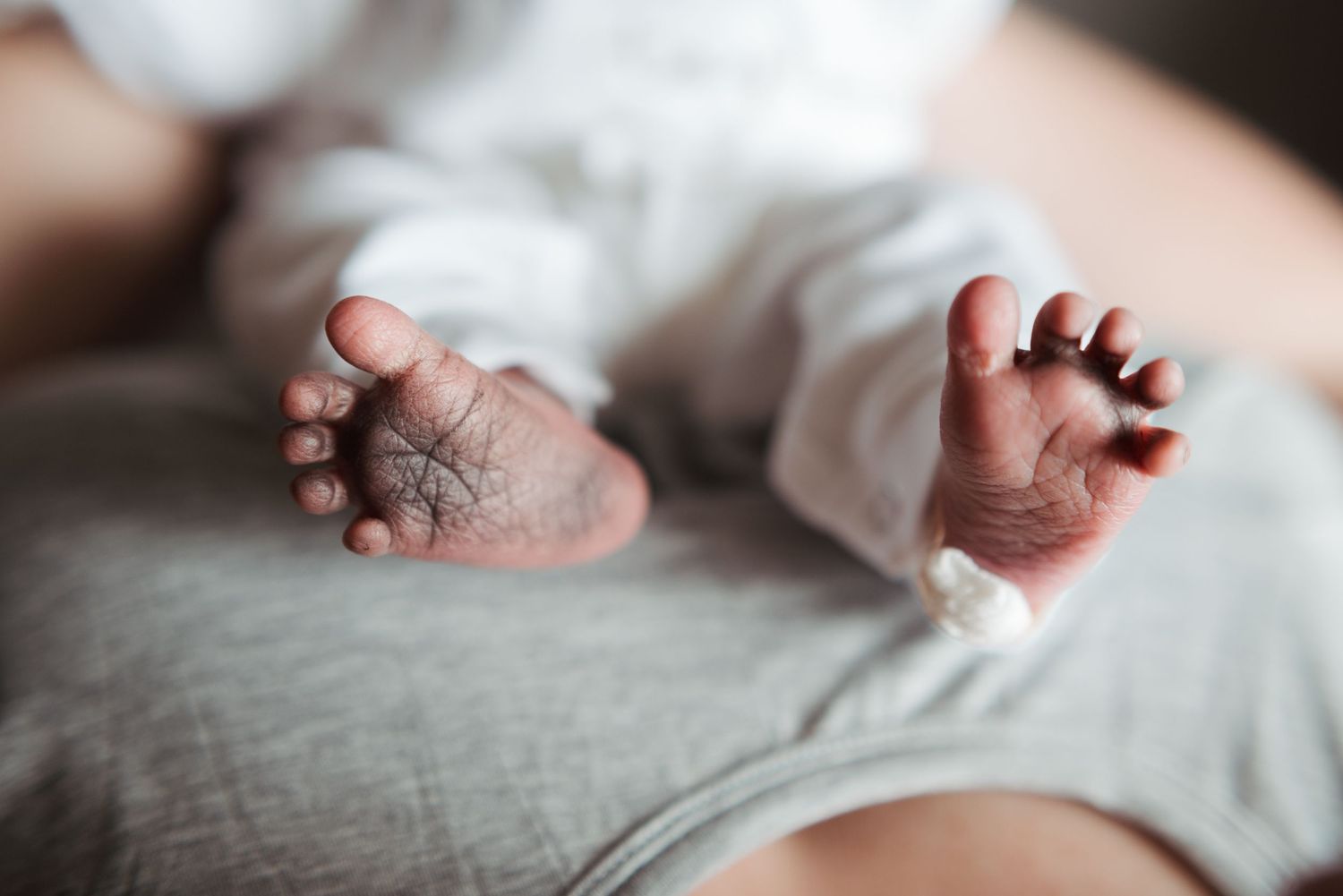 Close-up macro shot of newborn baby feet showing tiny toes against white textile.