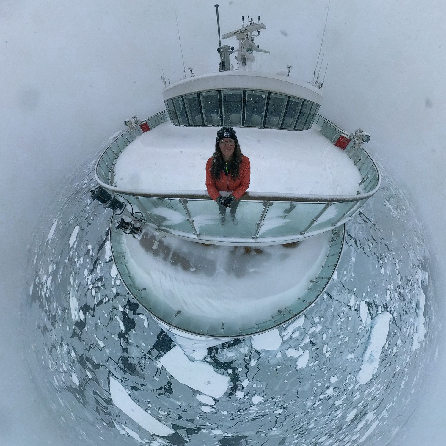Wide angle view from ship's bridge deck covered in snow with nautical equipment visible.