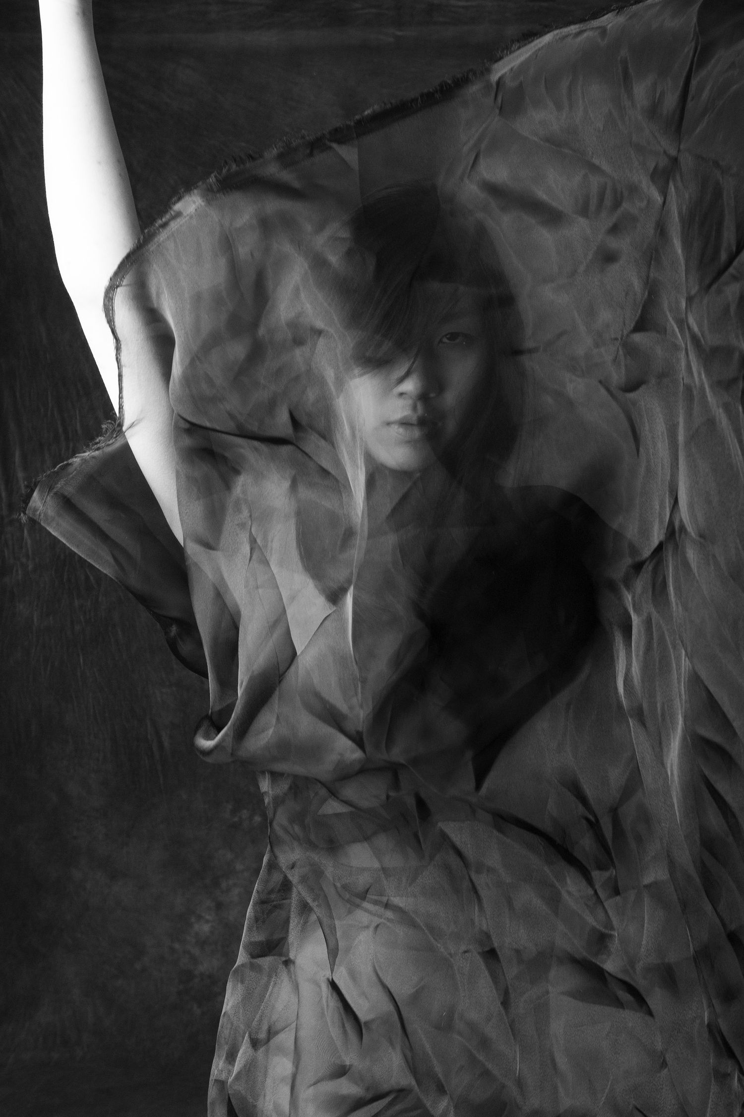 Black and white artistic portrait of a woman wrapped in crinkled sheer fabric. Boudoir photography Christchurch