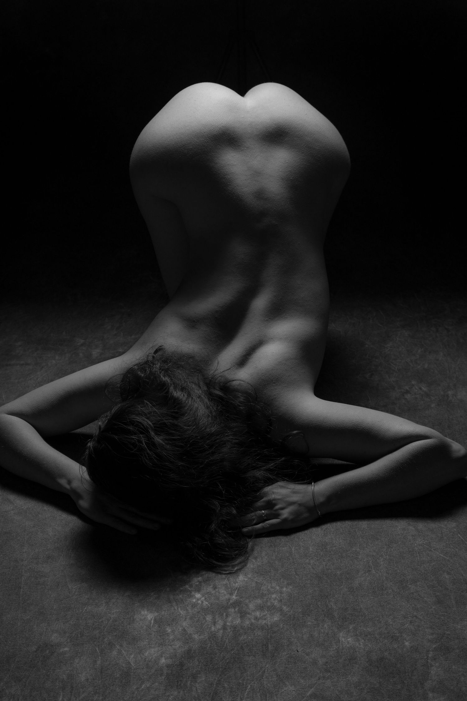 Black and white fine art nude of a woman lying face down, emphasizing back and body contours. Boudoir photography Christchurch bodyscape